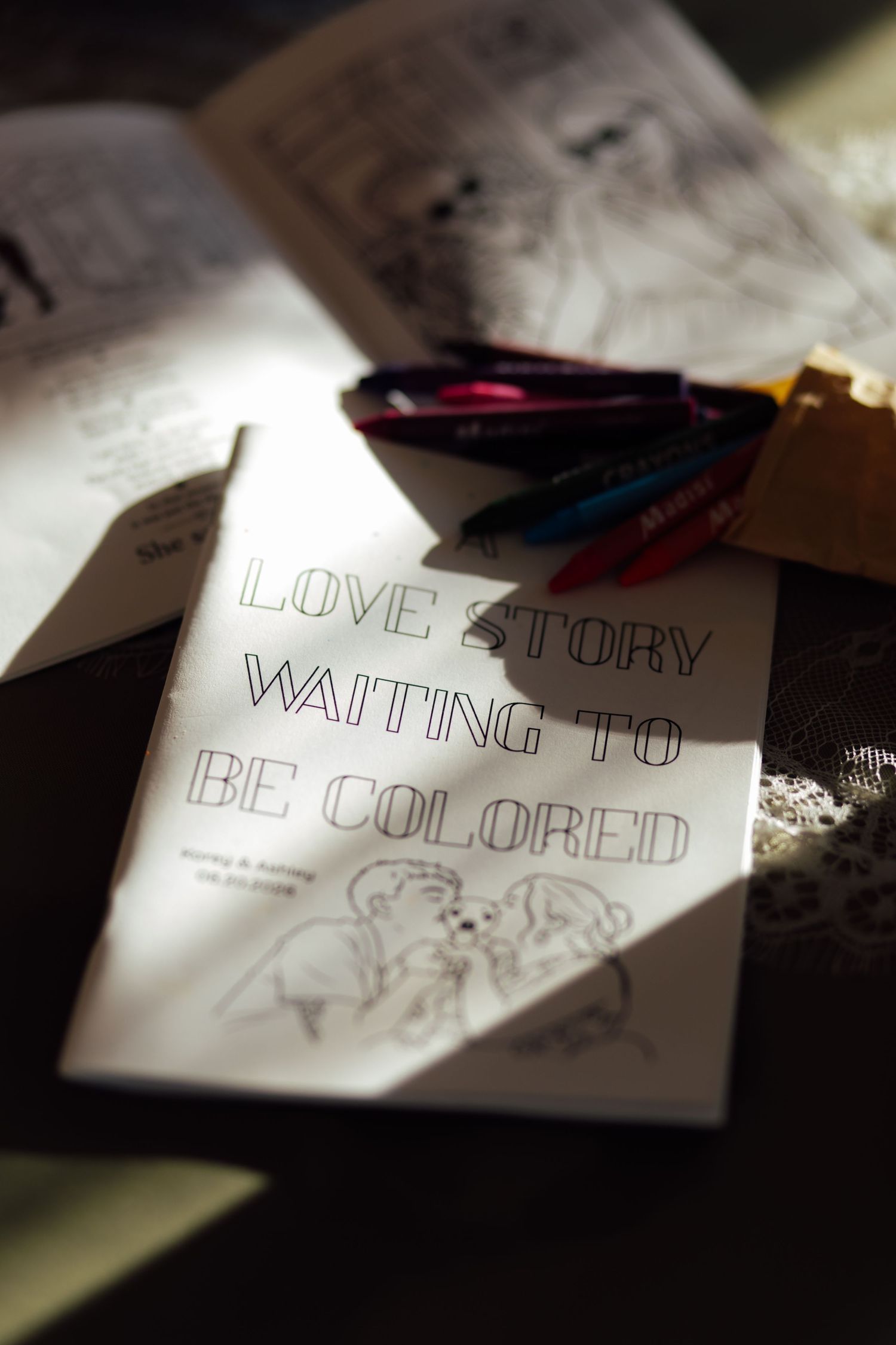 A coloring book titled Love Story Waiting to Be Colored with crayons, perfect for a unique wedding activity.