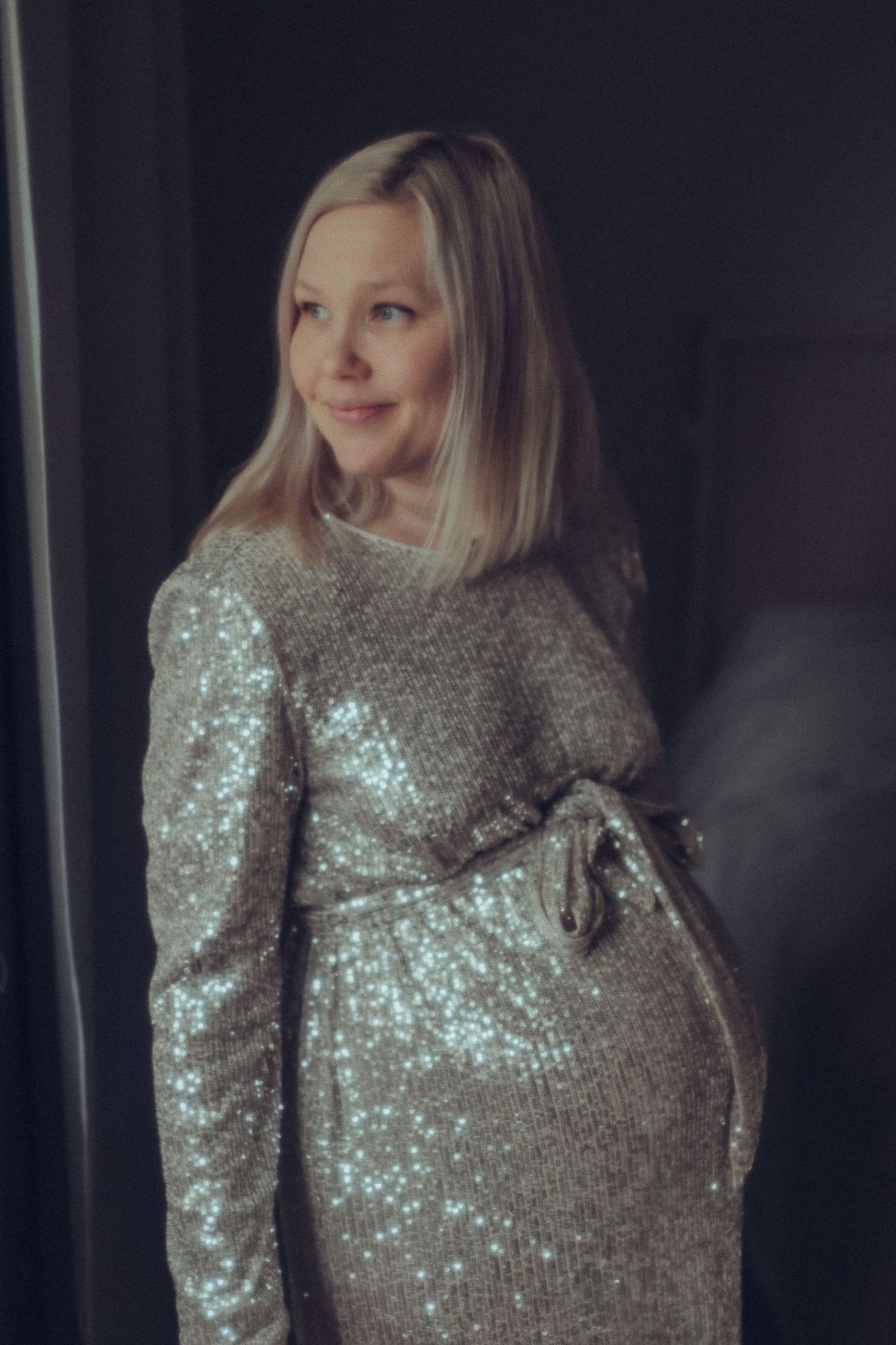 Raskaana oleva nainen studiossa, pehmeä valo ja elegantti, herkkä tunnelma