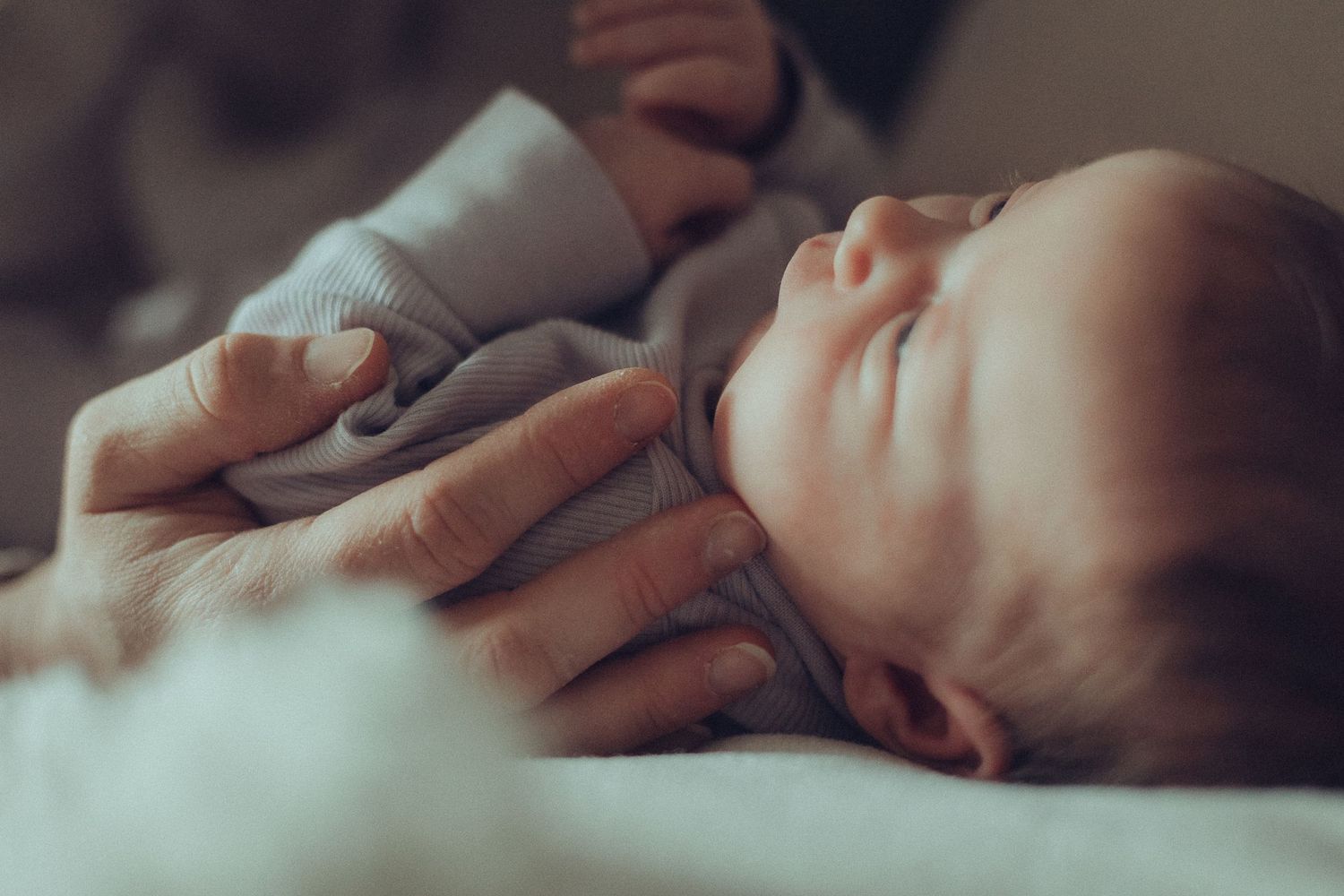 Vastasyntynyt vauva vanhemman käsissä, herkkä ja rauhallinen hetki