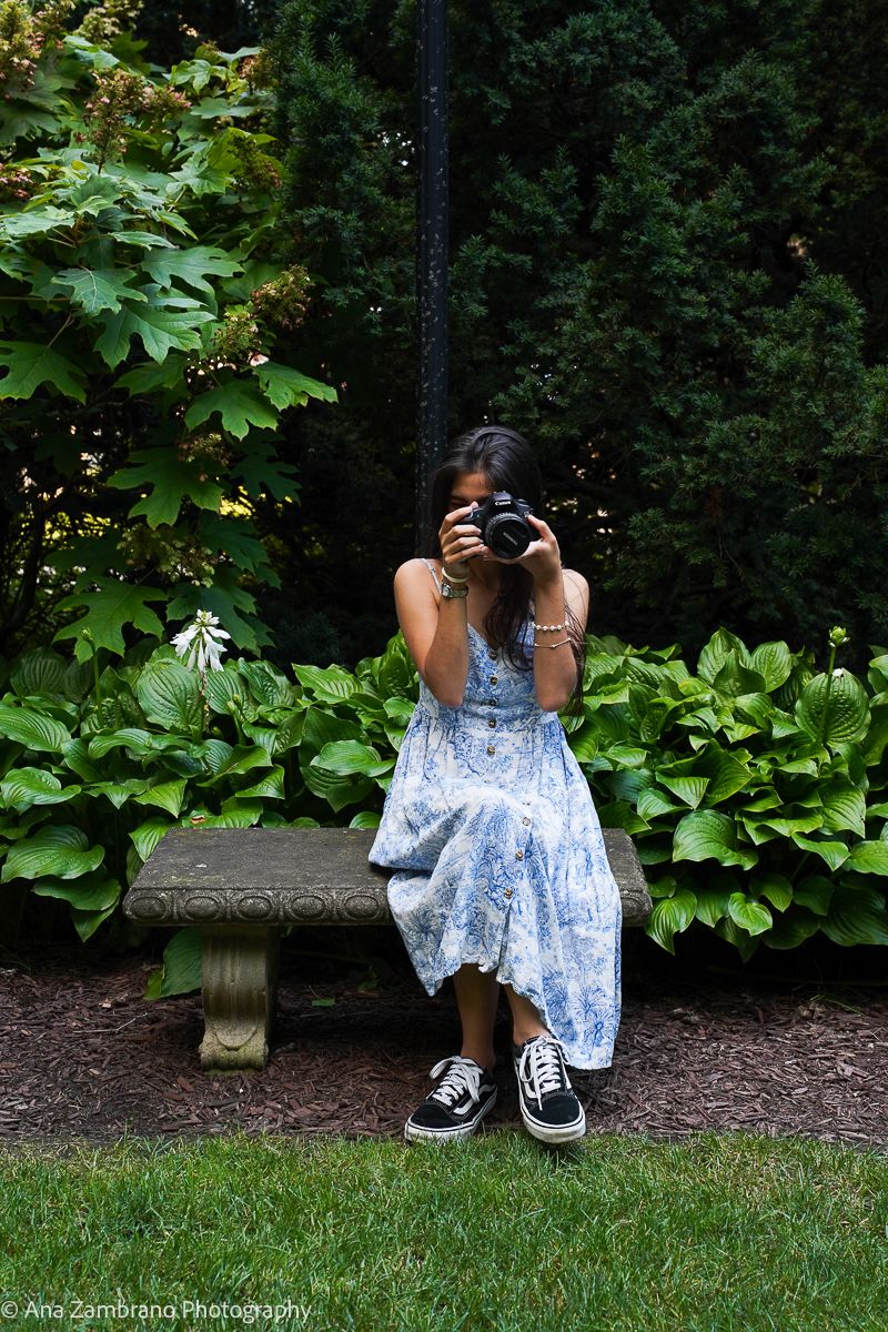 Photographer holding a camera while sitting on a garden bench at Kelton House Museum in Columbus Ohio