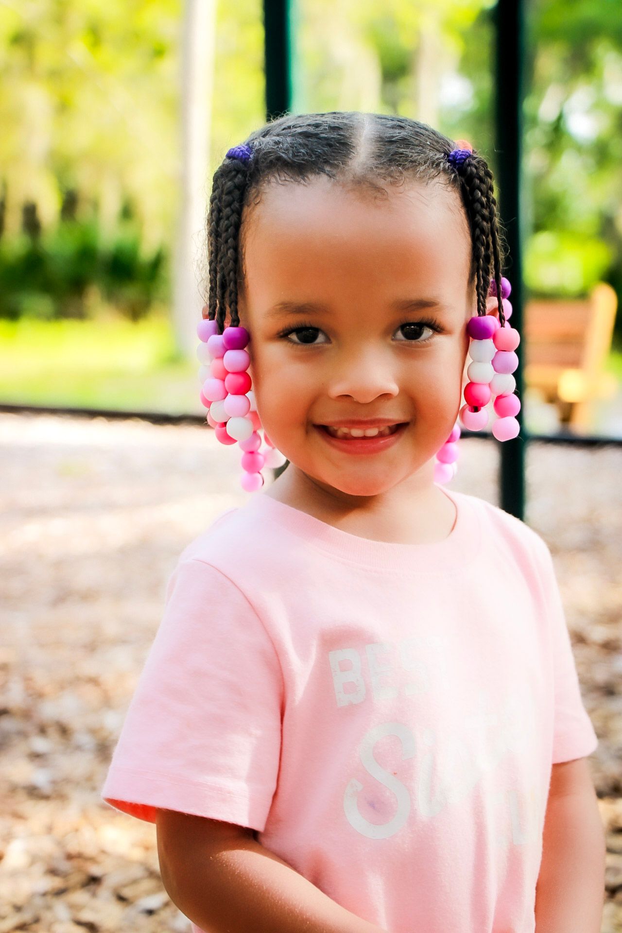 A young girl childhood portrait shot with vibrant pink and green colors smiling at the camera and posing.