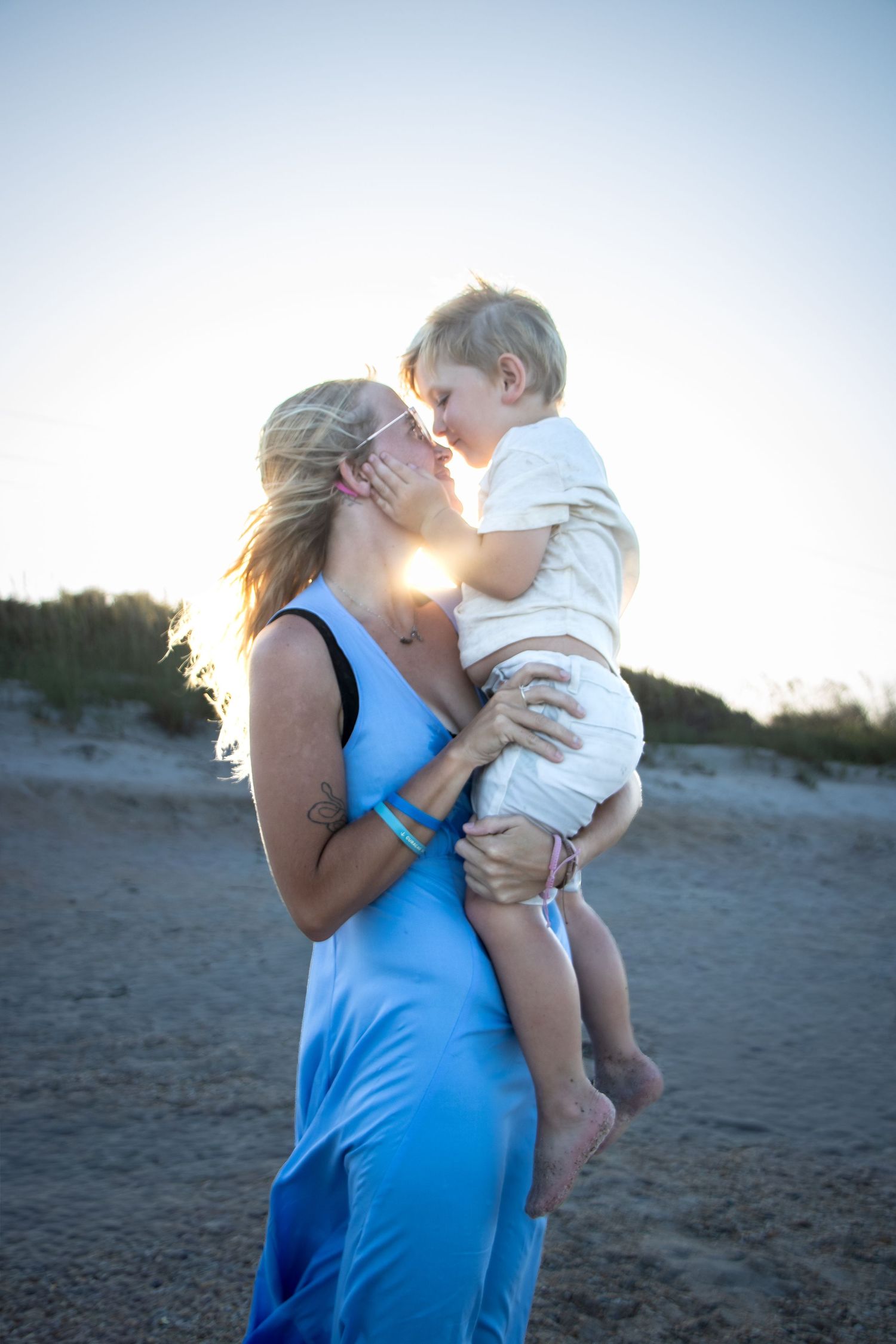 A mom and her son kissing on the beach in jacksonville, florida for a family portrait and childhood milestone during the sunset.