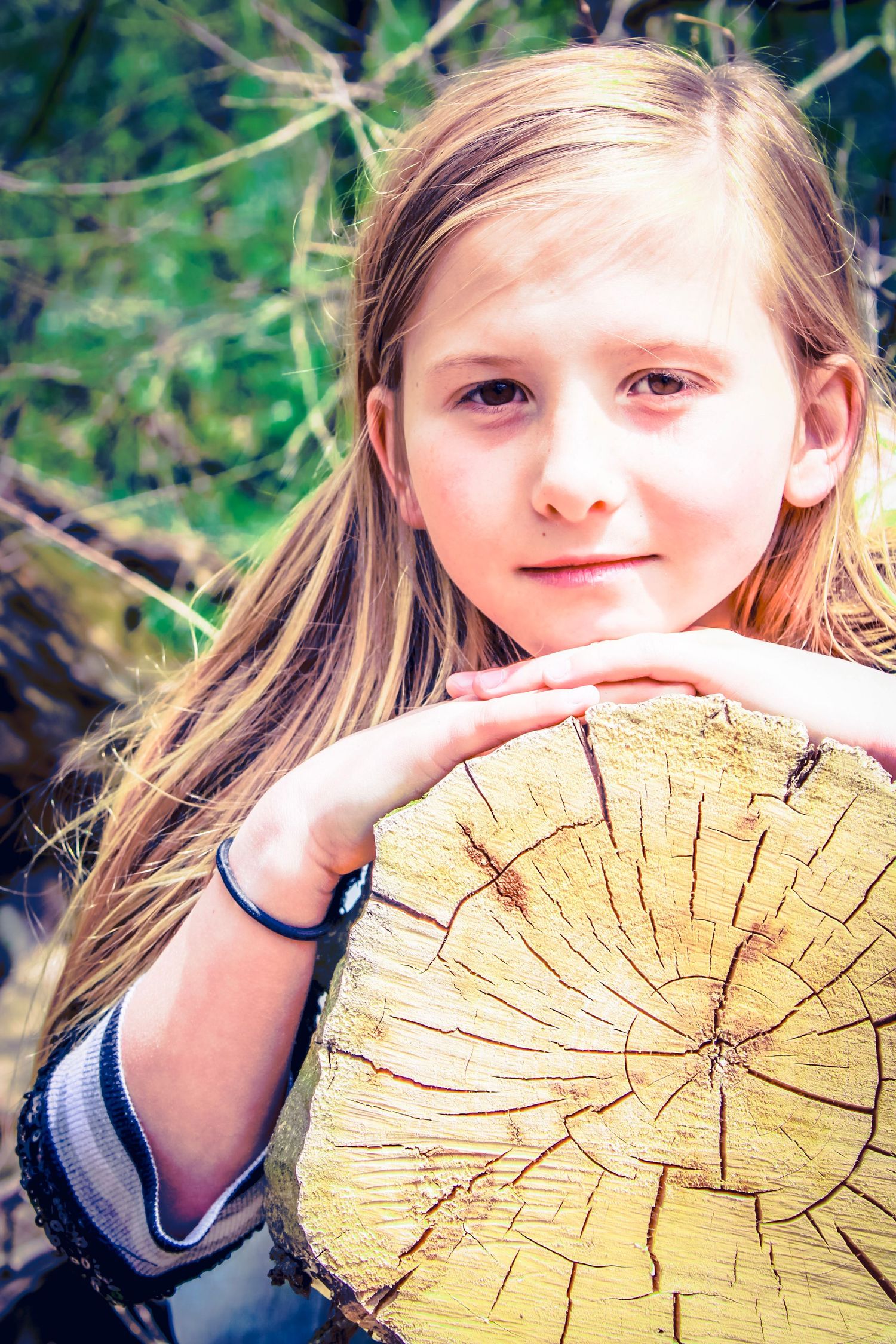 A girl laying on a tree stump with beautiful vibrant colors in the background