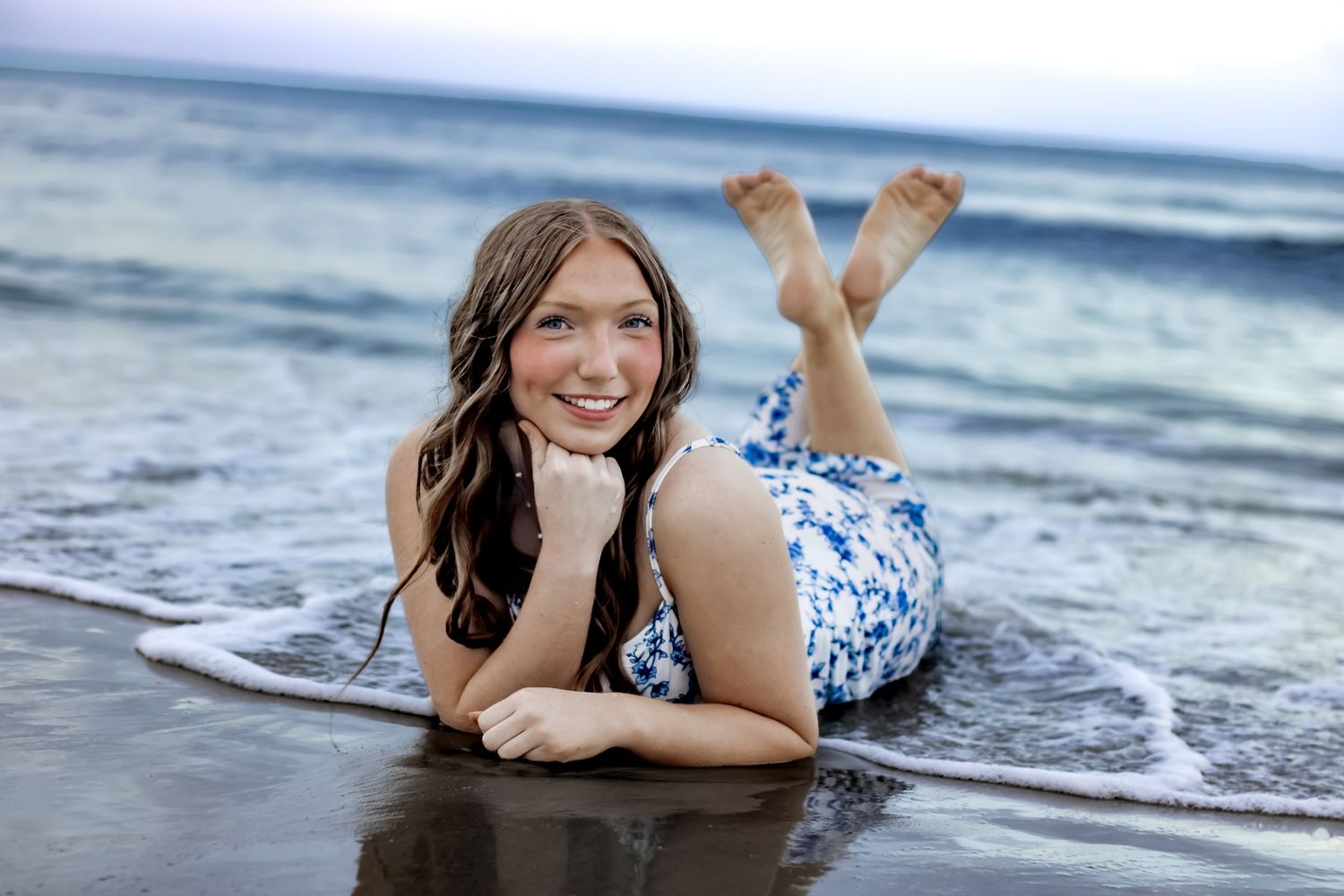 A senior portrait of a girl laying in the Atlantic ocean in crescent beach Florida laying in the sand and waves.