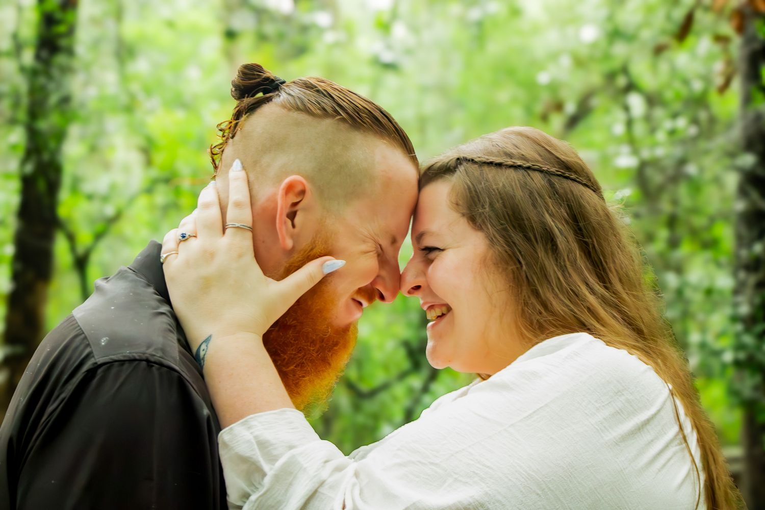 Couple touching foreheads and smiling romantically outdoors surrounded by lush green trees at their engagement session in Fruit Cove, Fl.