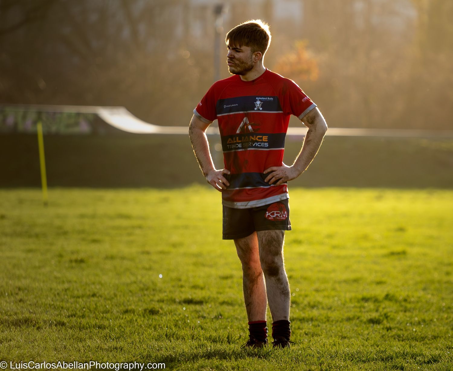 A weary rugby player stands on the pitch during golden hour, captured by Luis Carlos Abellan Photography in the South East of England.