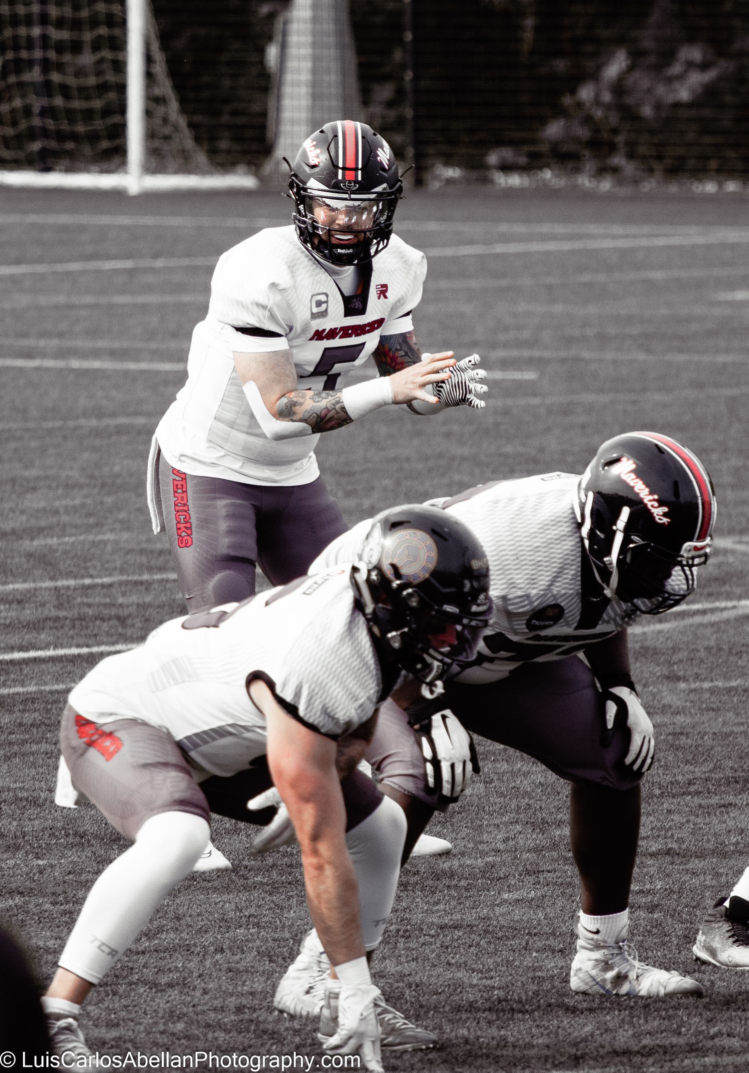 American football quarterback ready to snap the ball to teammates during a match in the UK, photographed by Luis Carlos Abellan.