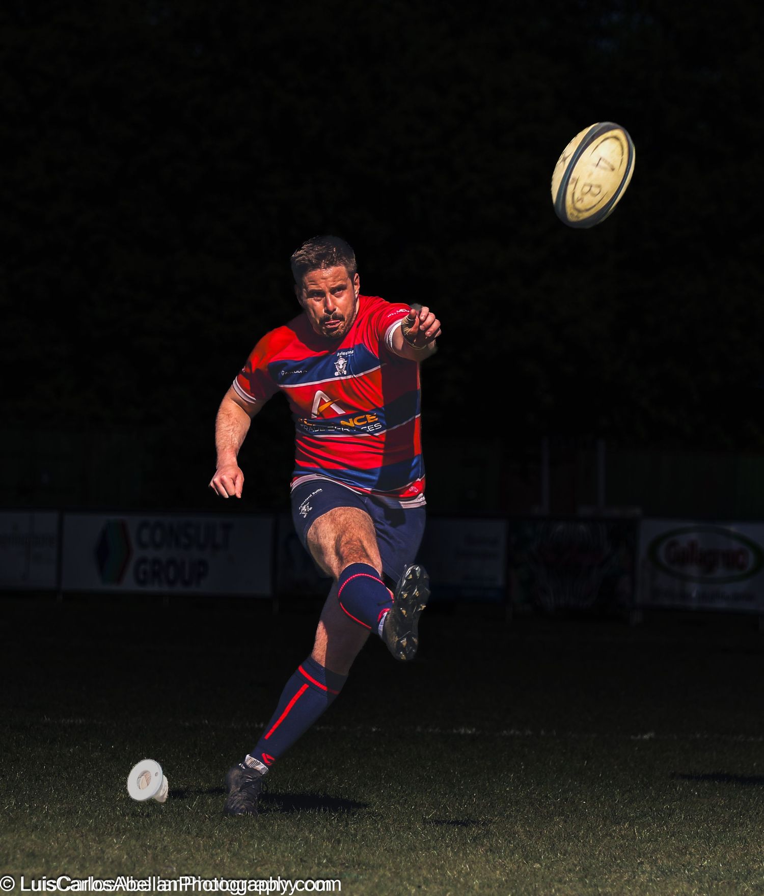 Rugby player kicking the ball during a night match in South East England. Professional sports photography by Luis Carlos Abellan.