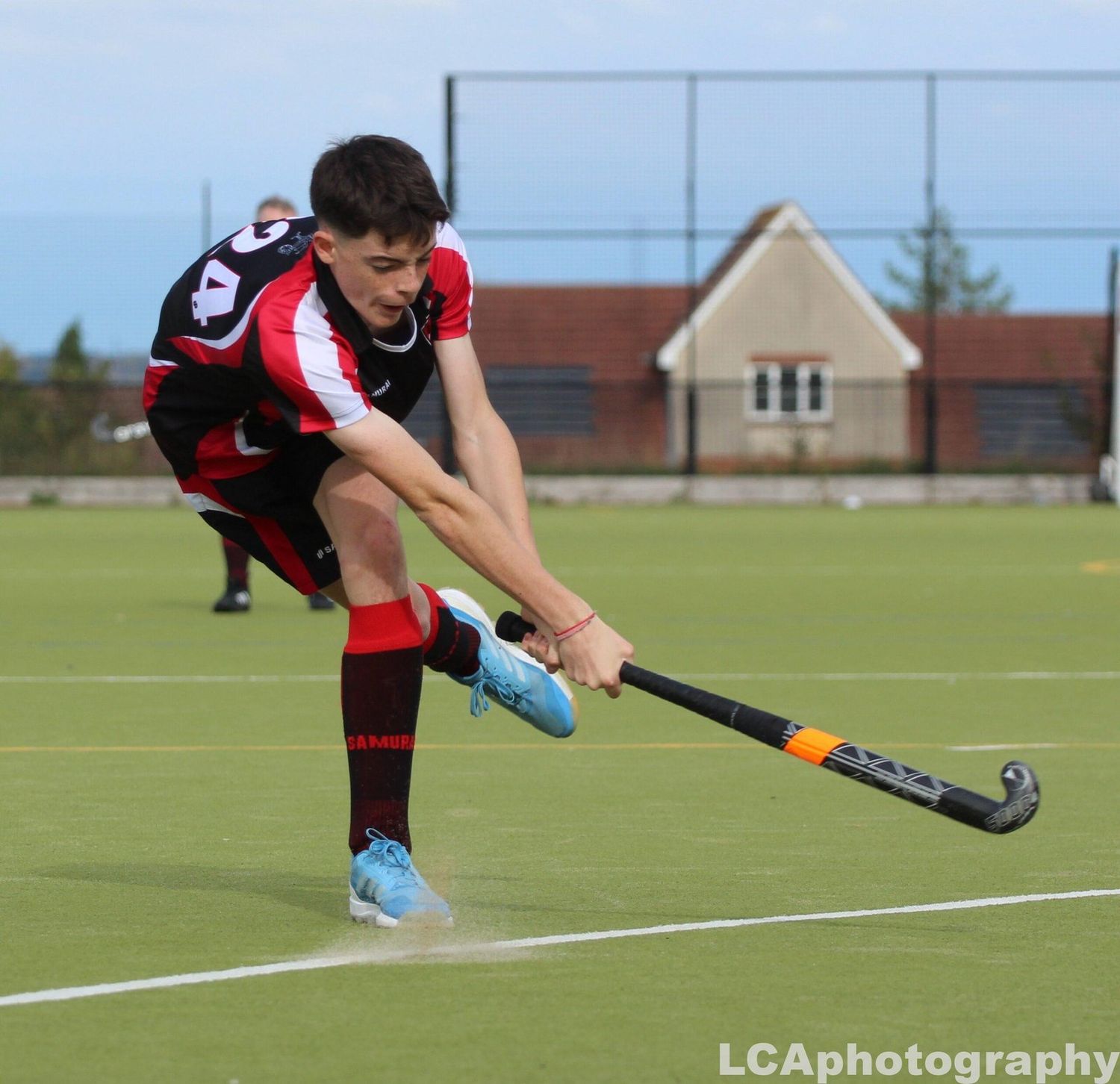 Field hockey player performing a powerful strike on the pitch during a match in the South East, captured by Luis Carlos Abellan Photography.