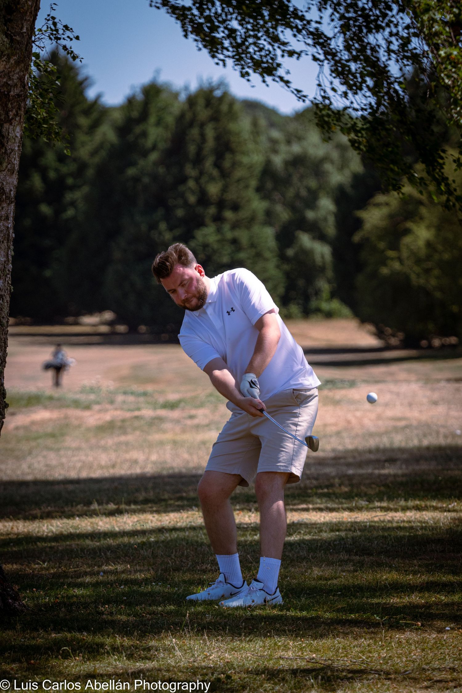 A male golfer swinging a club on a sunny fairway, captured in crisp action during a local golf event in Kent.