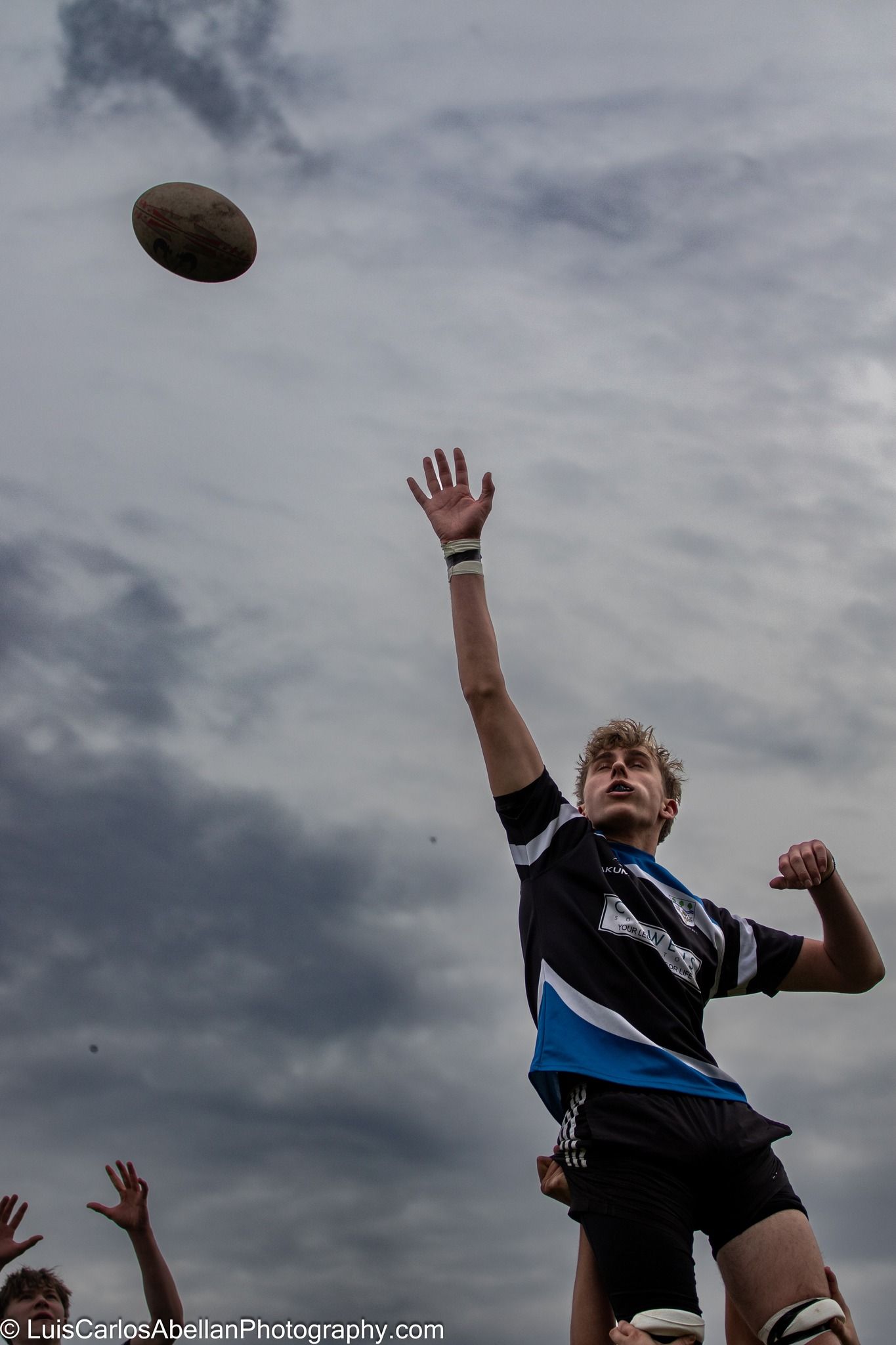 A rugby player leaping high in a lineout to catch the ball during a match in the South East, by Luis Carlos Abellan Photography.