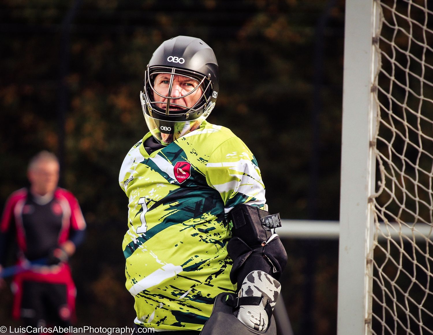 A hockey goalkeeper wearing full protective gear stands alert in the goal, photographed during a match in the South East by Luis Carlos