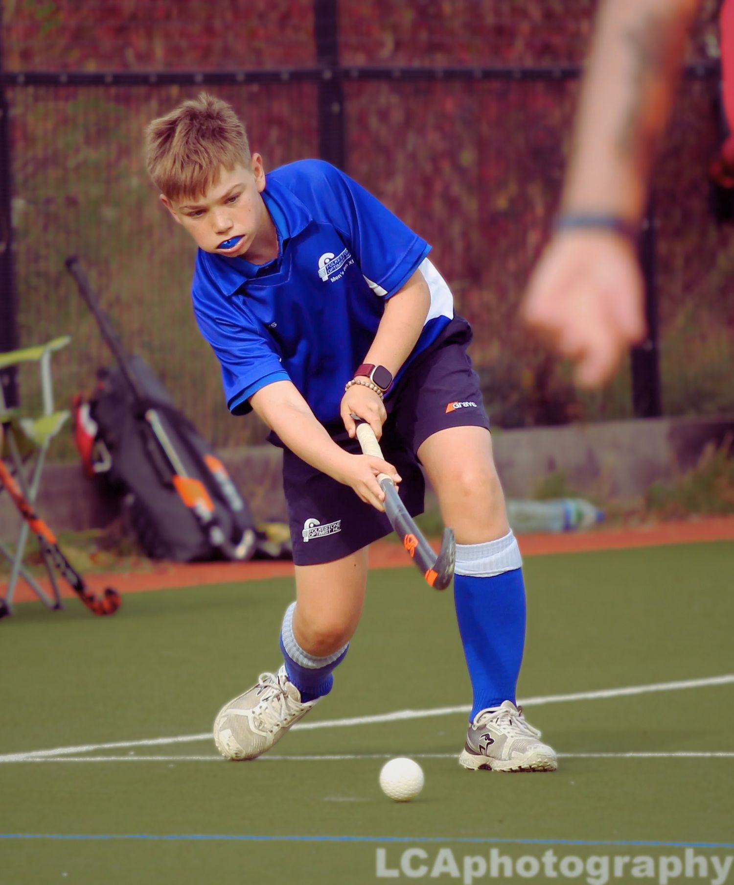 A young hockey player focused on controlling the ball during a match in the South East, photographed by LCAphotography.