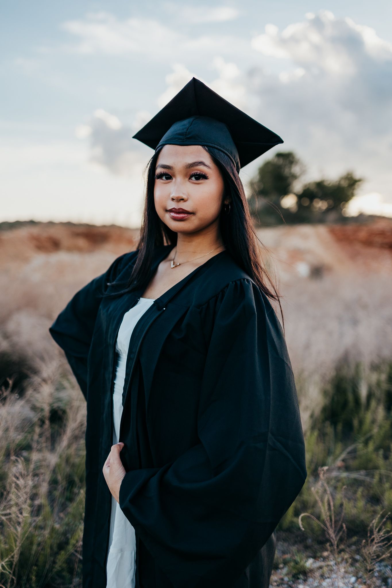 high school graduate in field in cap and gown in Waynesville mo for her last senior rep session