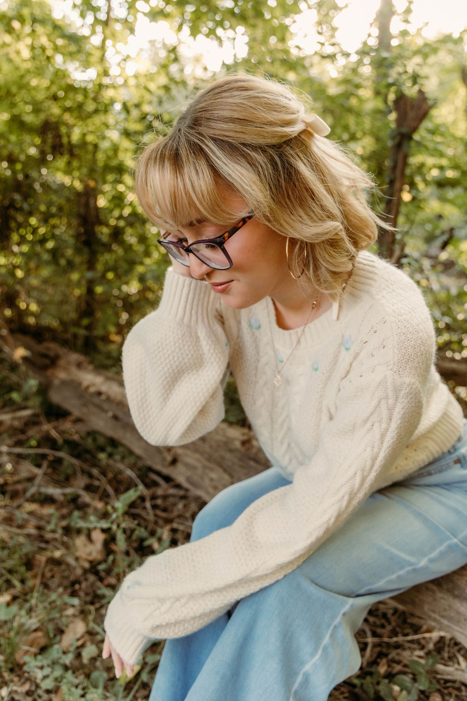 High school senior portrait in a cream sweater and glasses in a white sweater in an outdoor session in Missouri.