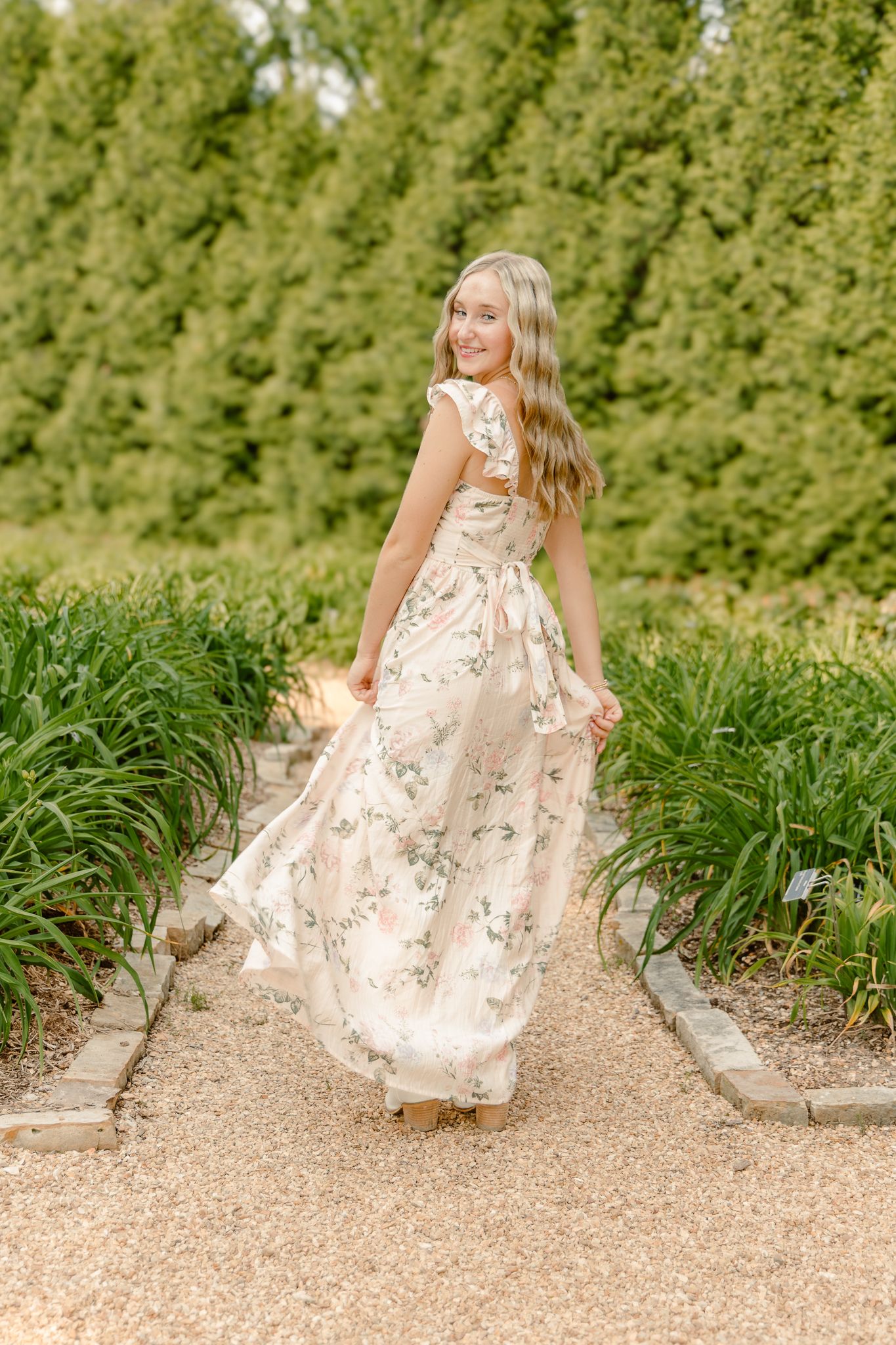 High school senior in a yellow flora dress in a flower field in Springfield, MO for her senior photoshoot.
