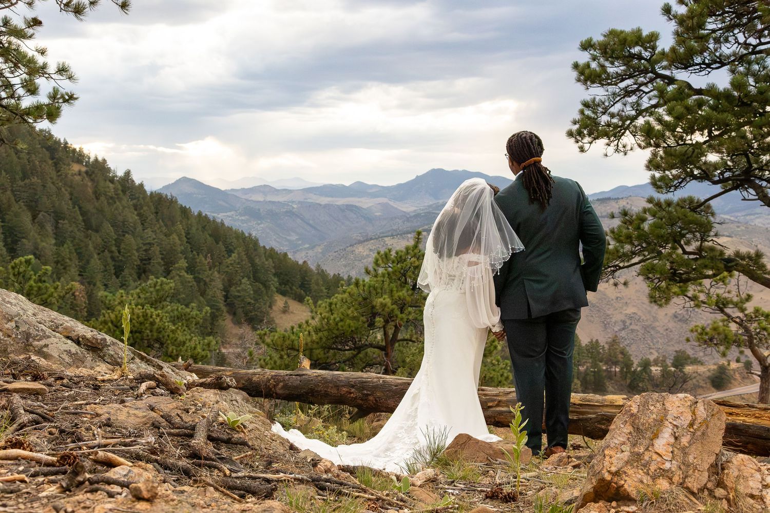 Bride and groom stand together overlooking stunning Rocky Mountain landscape on their wedding day.