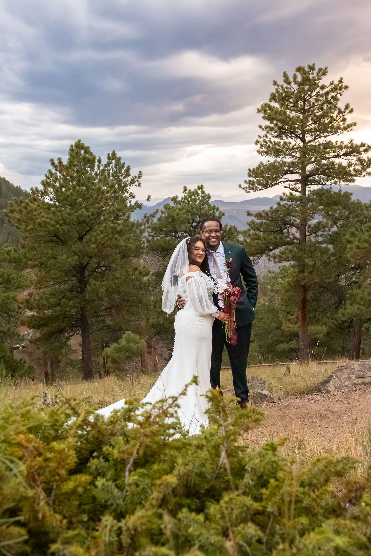 Bride and groom pose outdoors among pine trees and mountains in Colorado during a romantic sunset elopement.