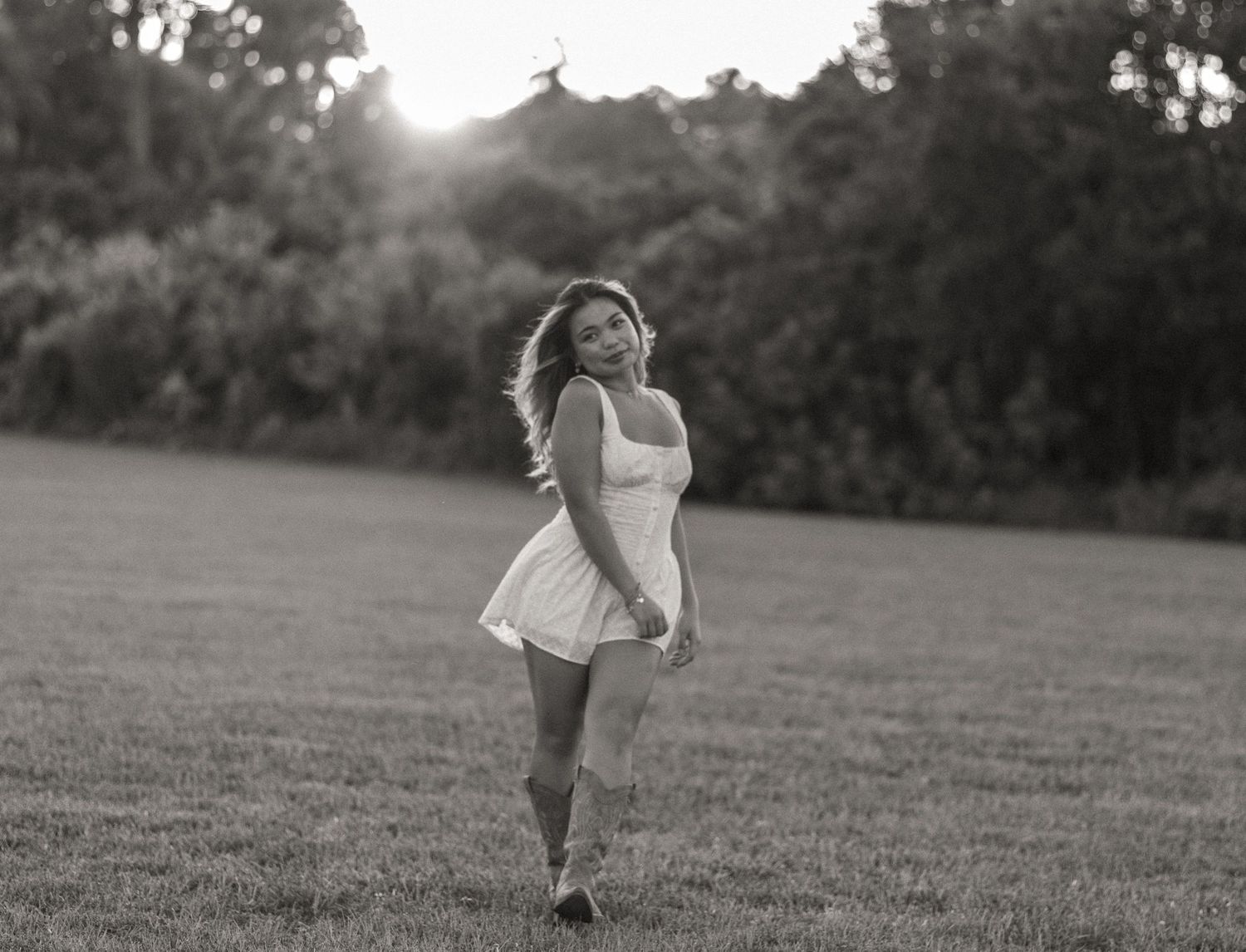 Black and white photo of a young woman posing outdoors.