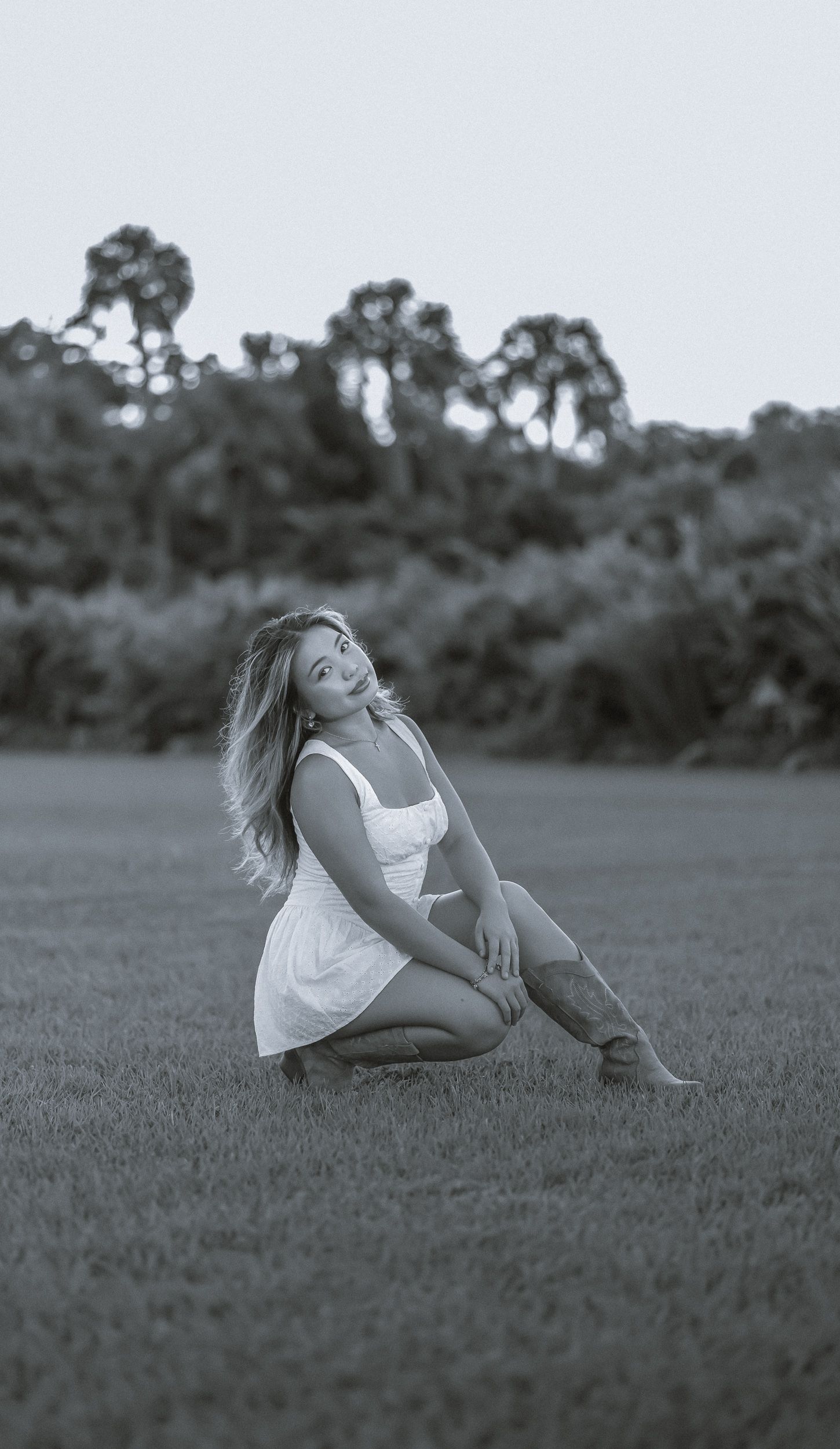 Black and white photo of a young woman posing in the field.