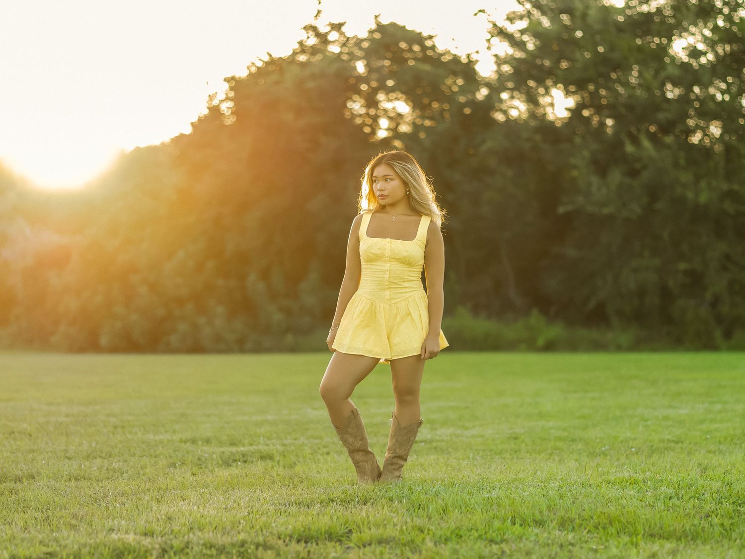 Young woman posing in a grassy field during an outdoor portrait session