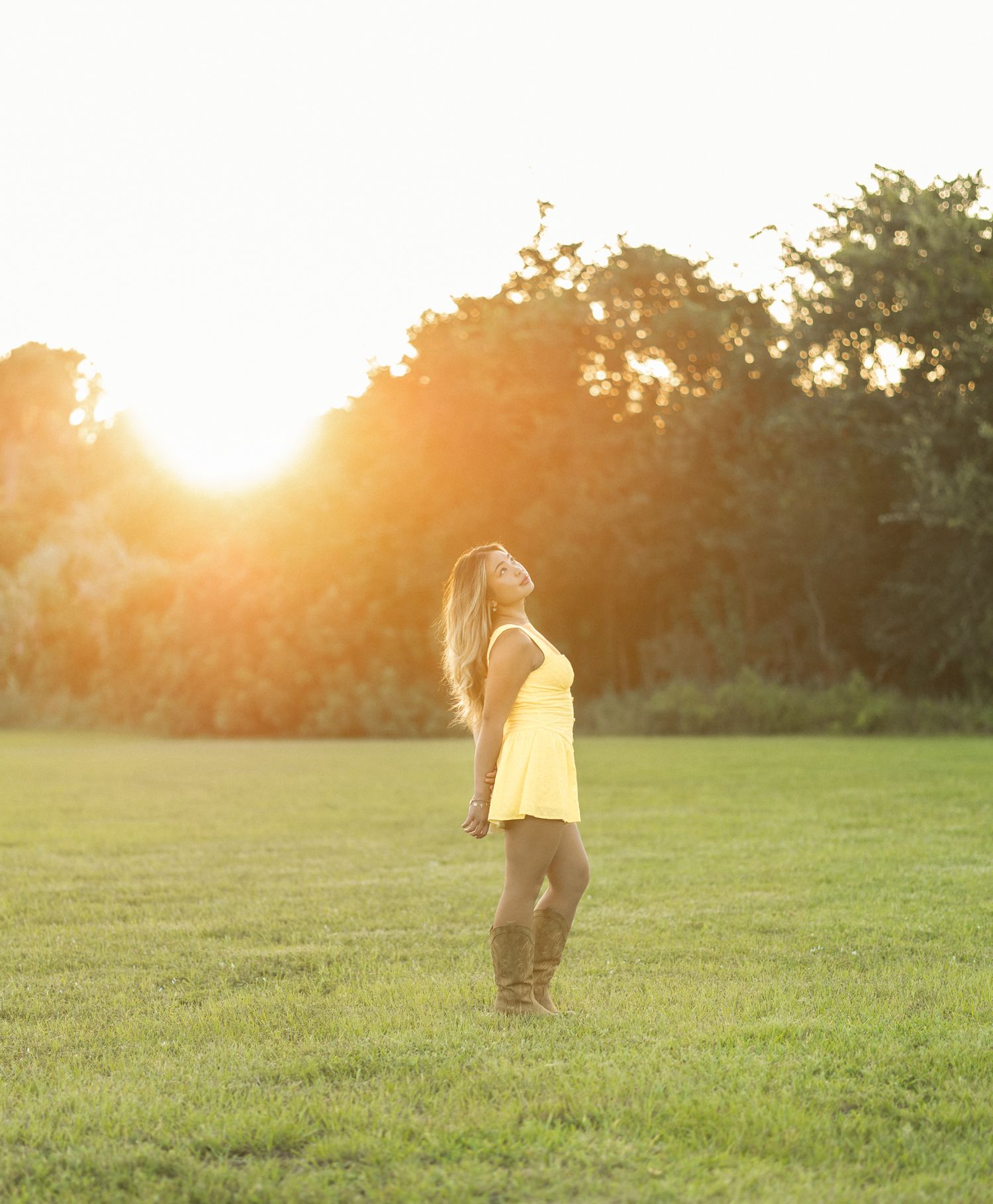 Young woman posing in a grassy field during an outdoor portrait session