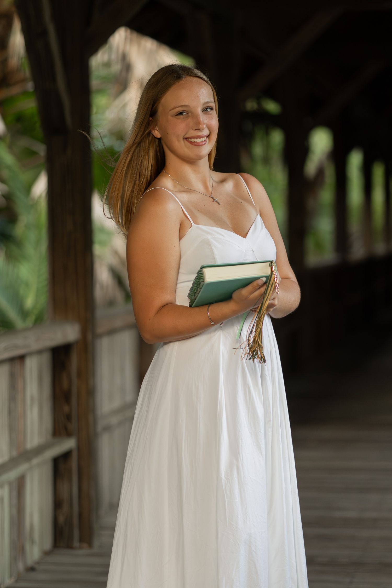 Full-length portrait of a young woman in a white dress on a covered walkway