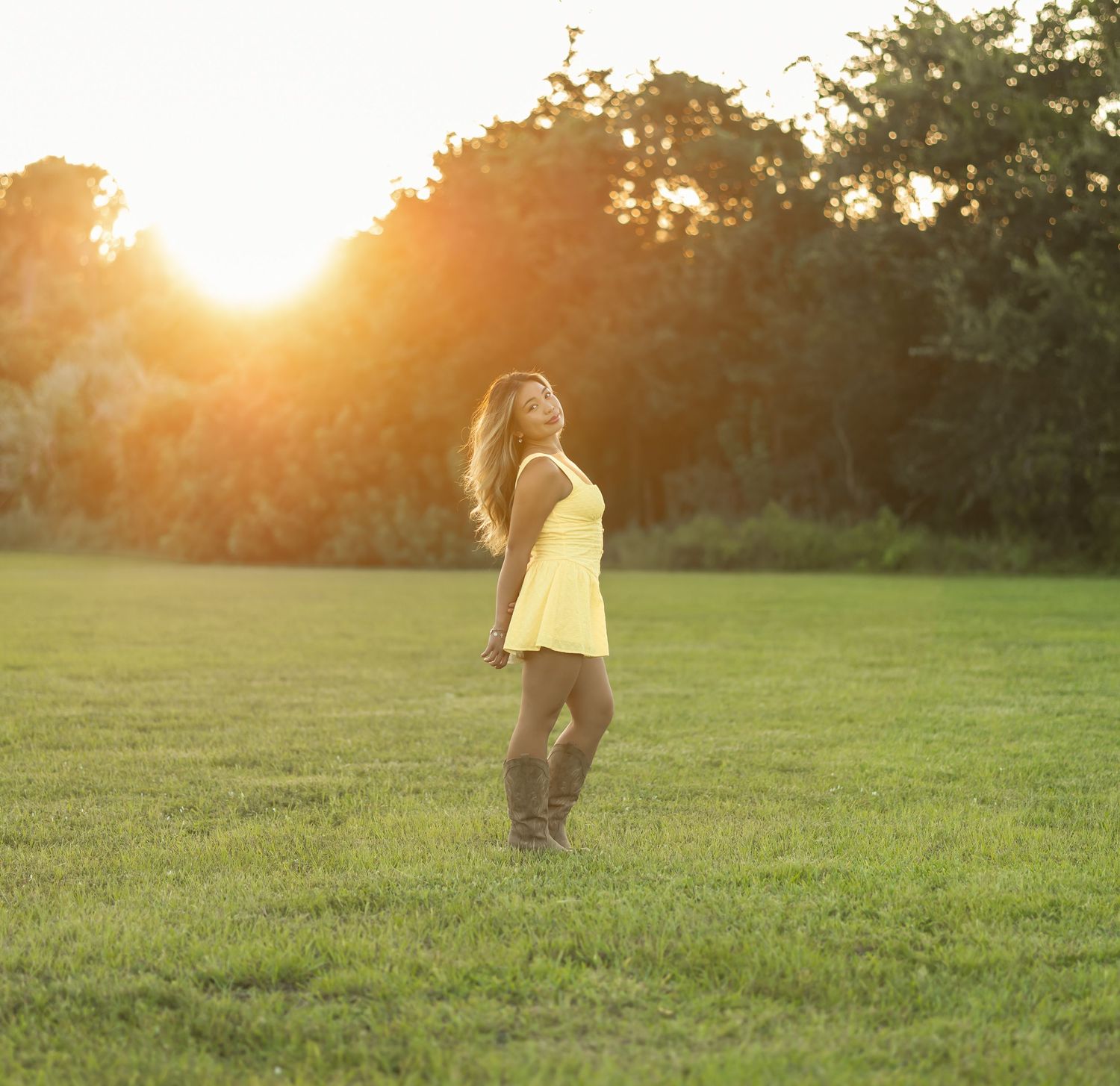 Golden-hour portrait of a young woman standing in a grassy field