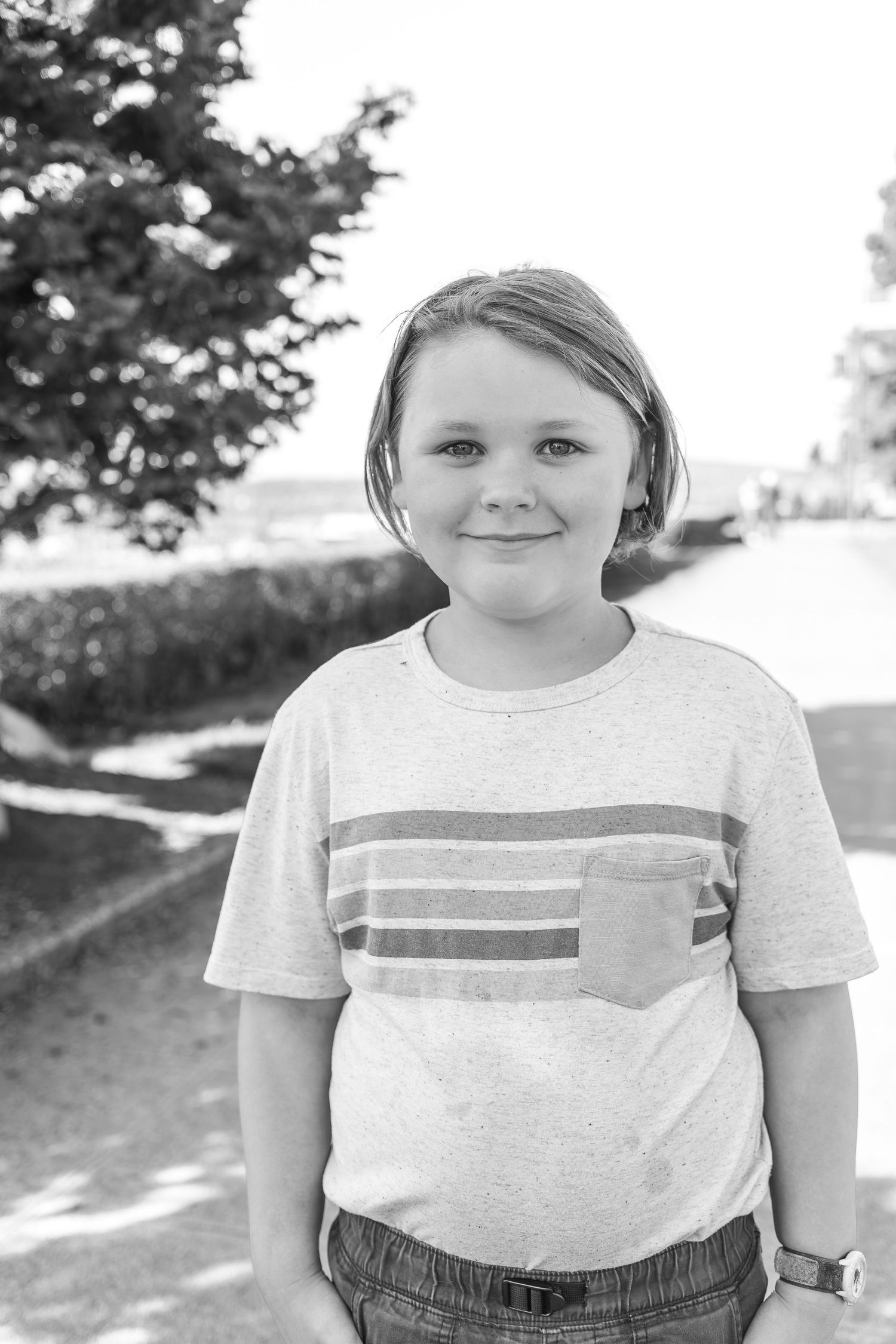 Young person in a casual striped gray t-shirt smiling in a bright setting.