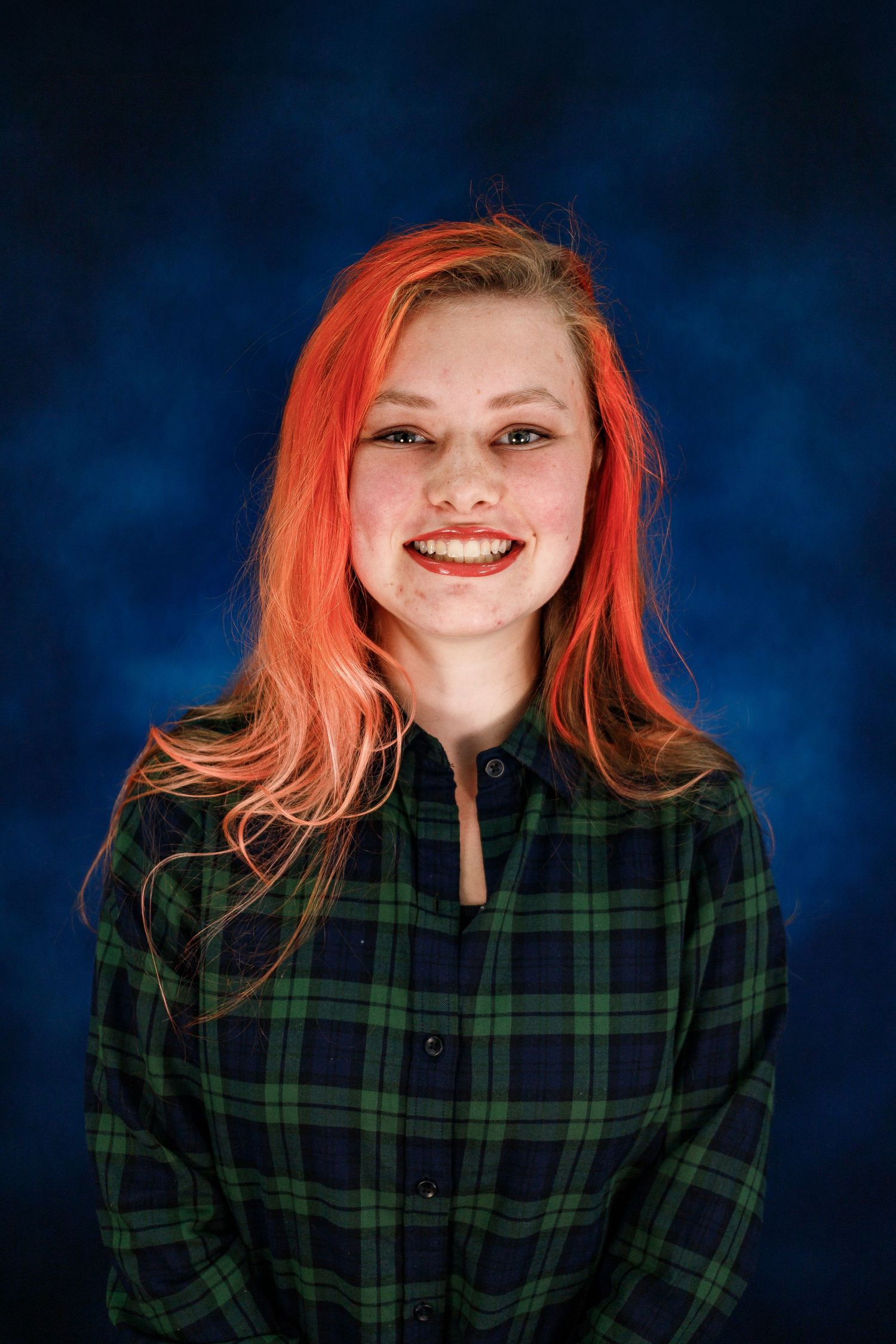 A series of portrait photos showing someone with vibrant red hair wearing a green and navy plaid shirt against a dark blue background.