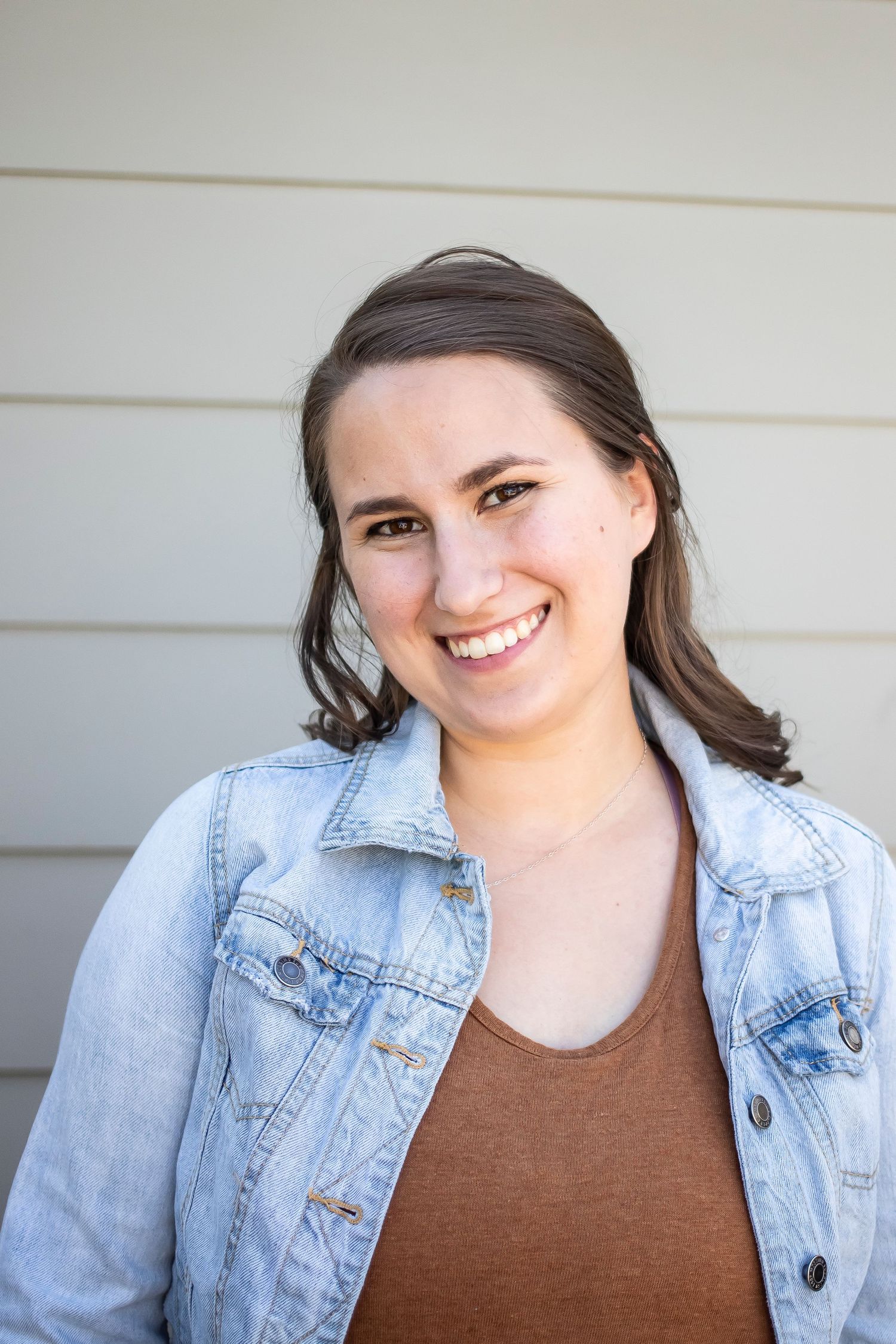 A series of four headshots showing someone in a denim jacket and brown top against a white wall.