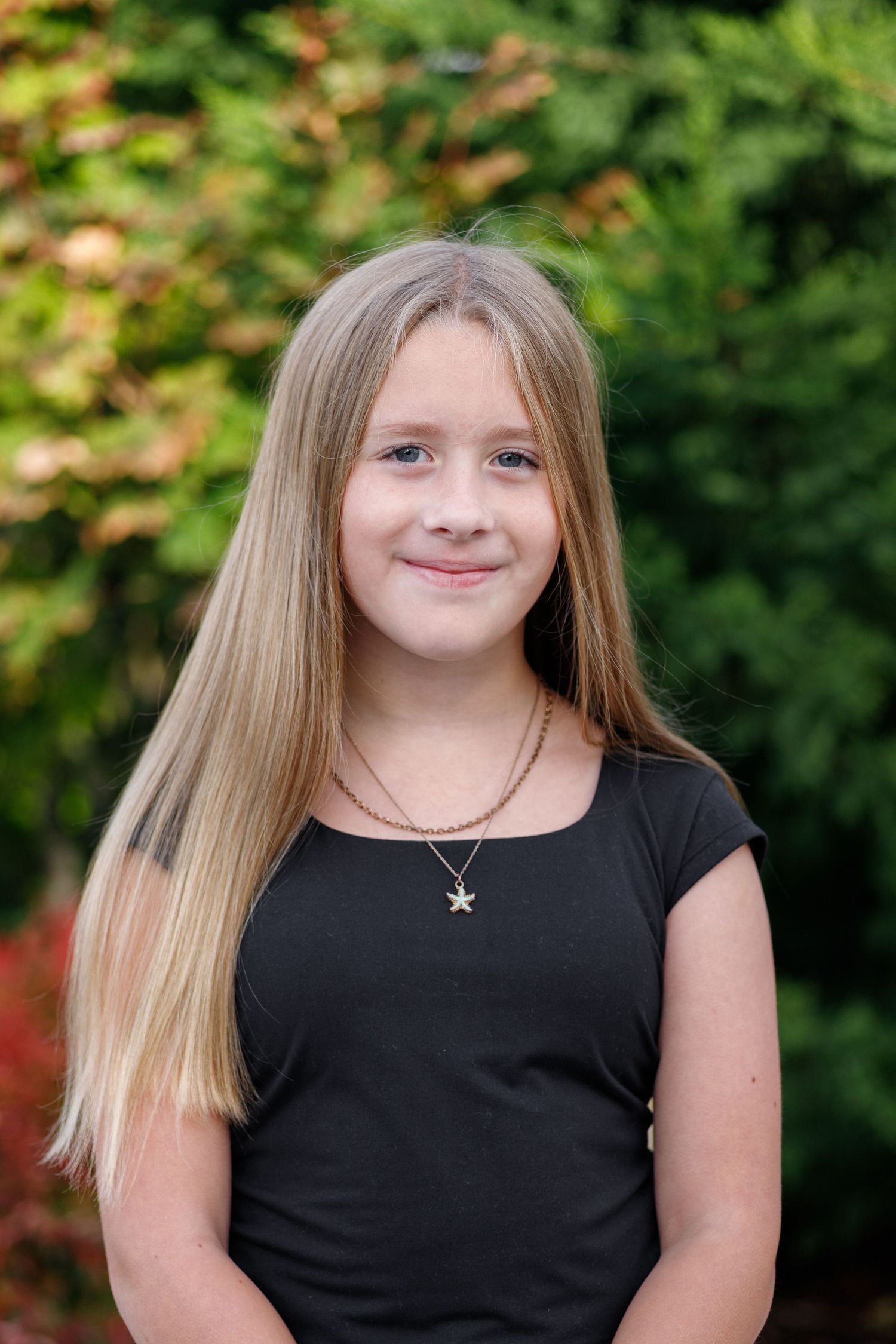 Portrait series showing progressive expressions while wearing a black top against a green natural background.
