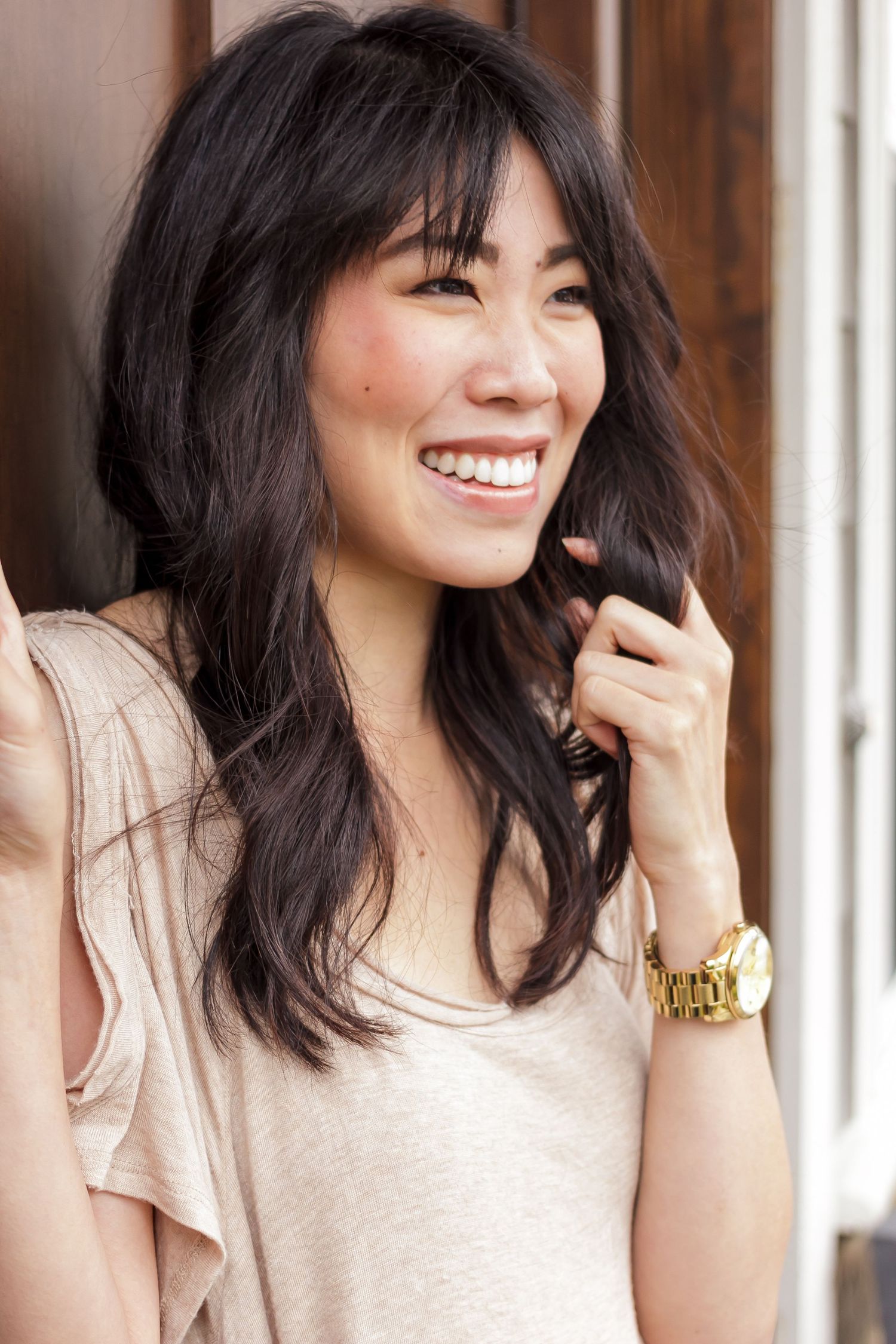 A series of four photos showing a woman with dark hair laughing and smiling naturally in a beige top with a gold watch.