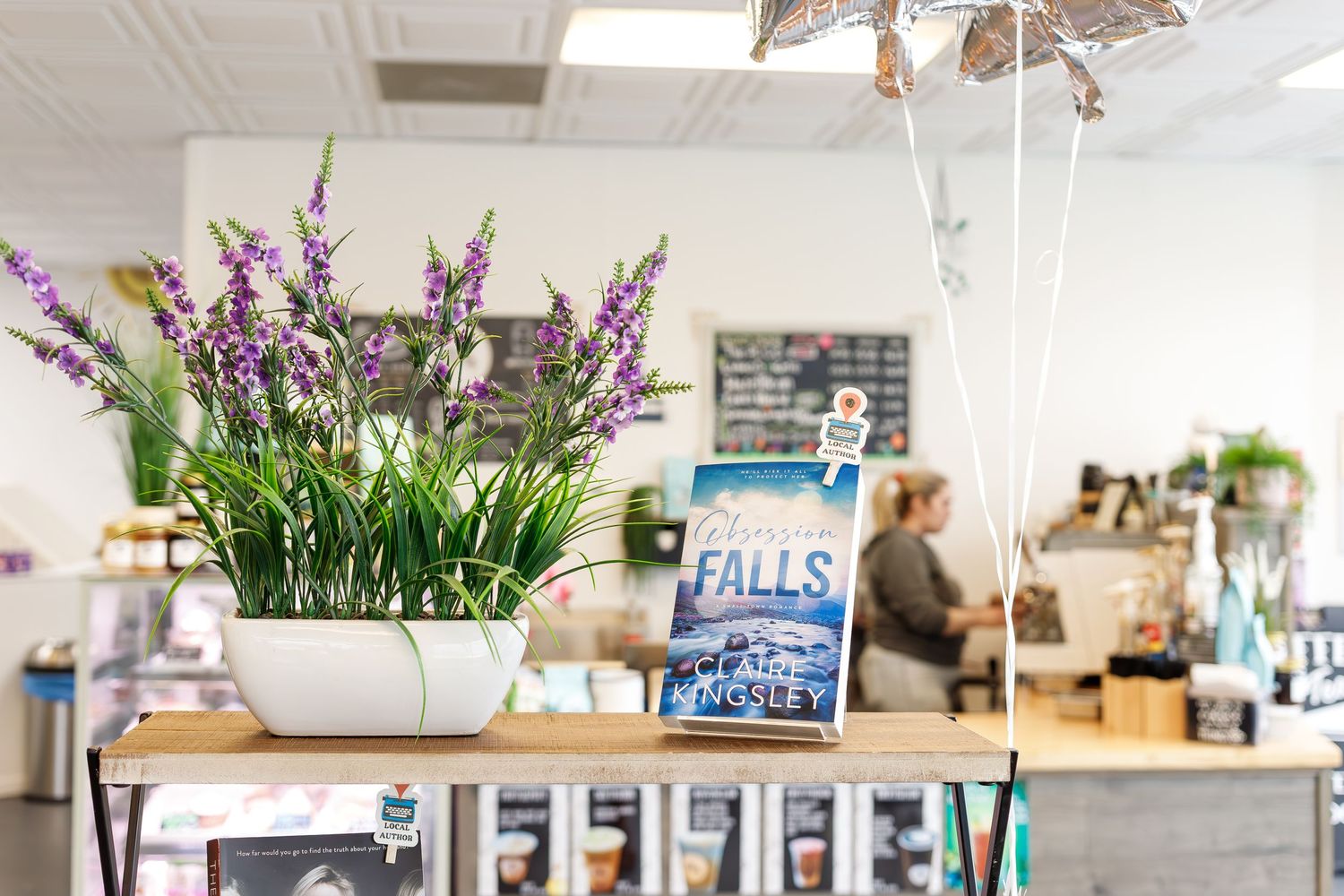 Retail shop interior with natural wood decor, hanging planters, and eclectic displays of boutique merchandise.