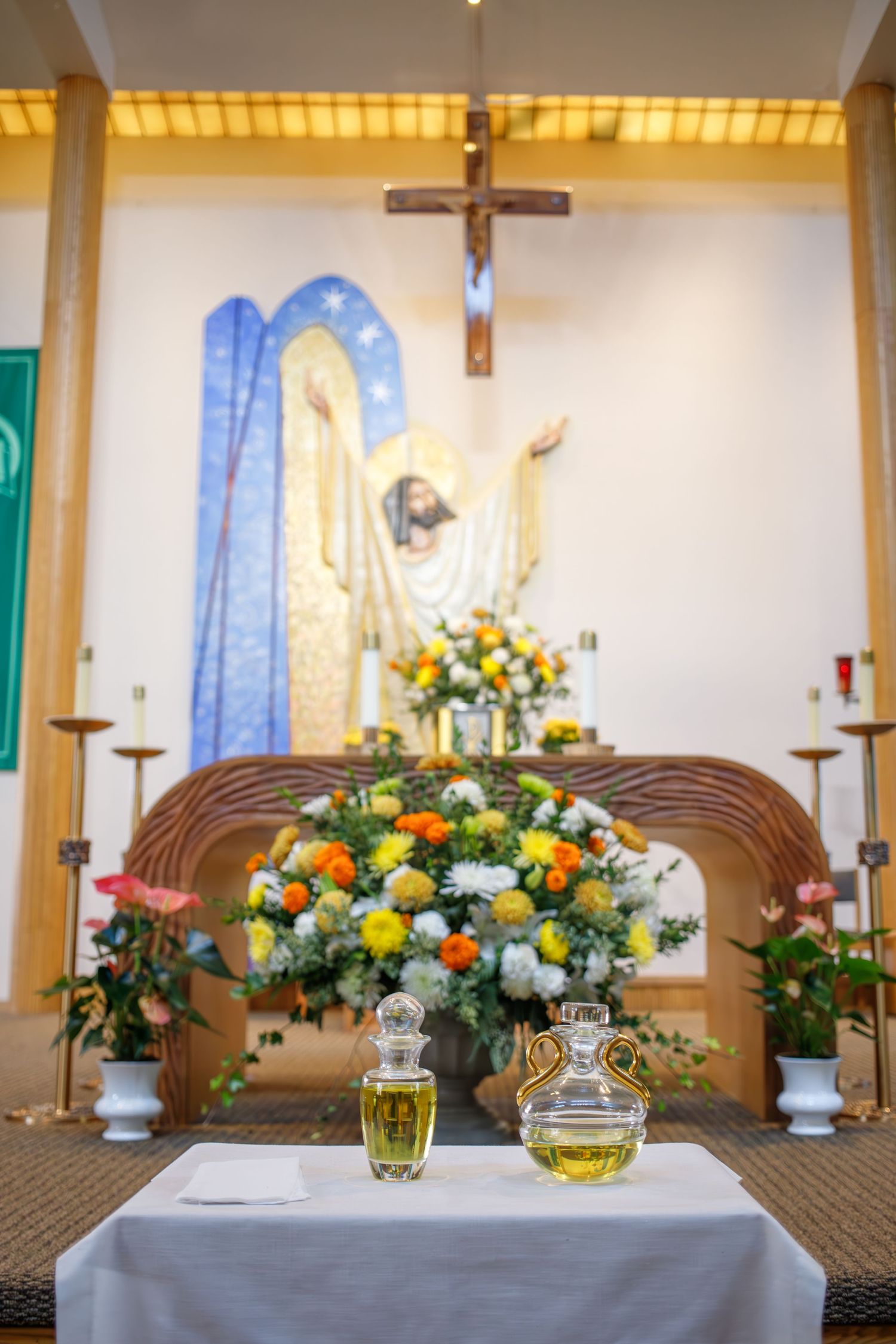 Church altar decorated with colorful floral arrangements, crucifix, and religious imagery with communion elements on white cloth.