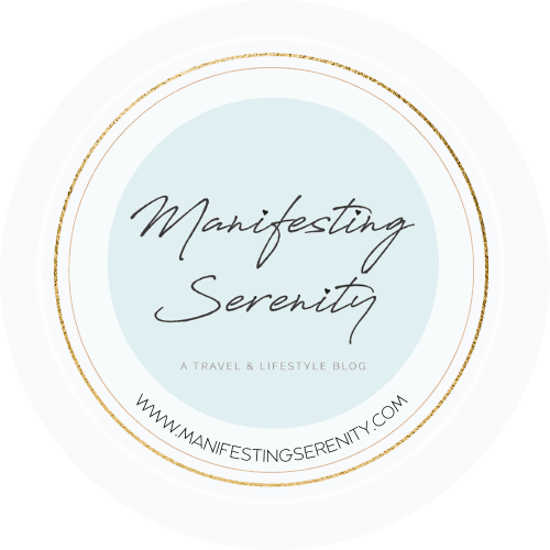 Circular logo design for 'Manifesting Serenity' travel and lifestyle blog with blue background and gold trim.