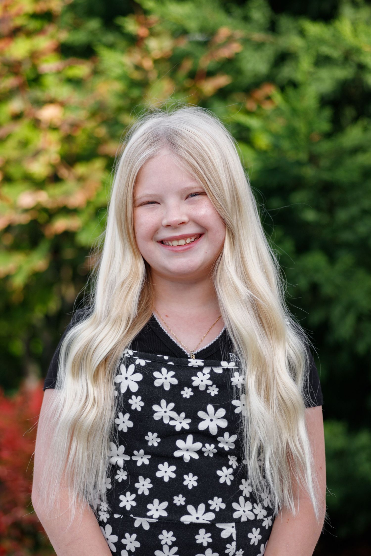 A sequence of photos showing a child with blonde hair wearing a black floral dress against a green outdoor background.