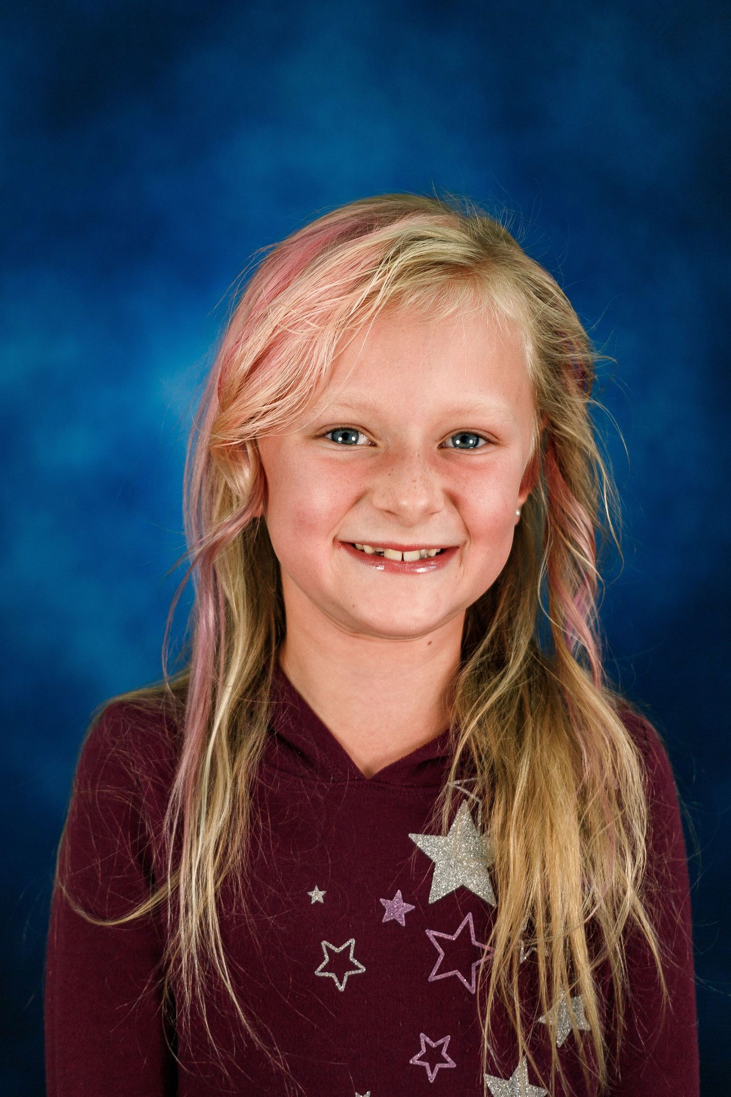 A series of school portrait photos showing a young student with blonde hair wearing a burgundy star-patterned sweater.