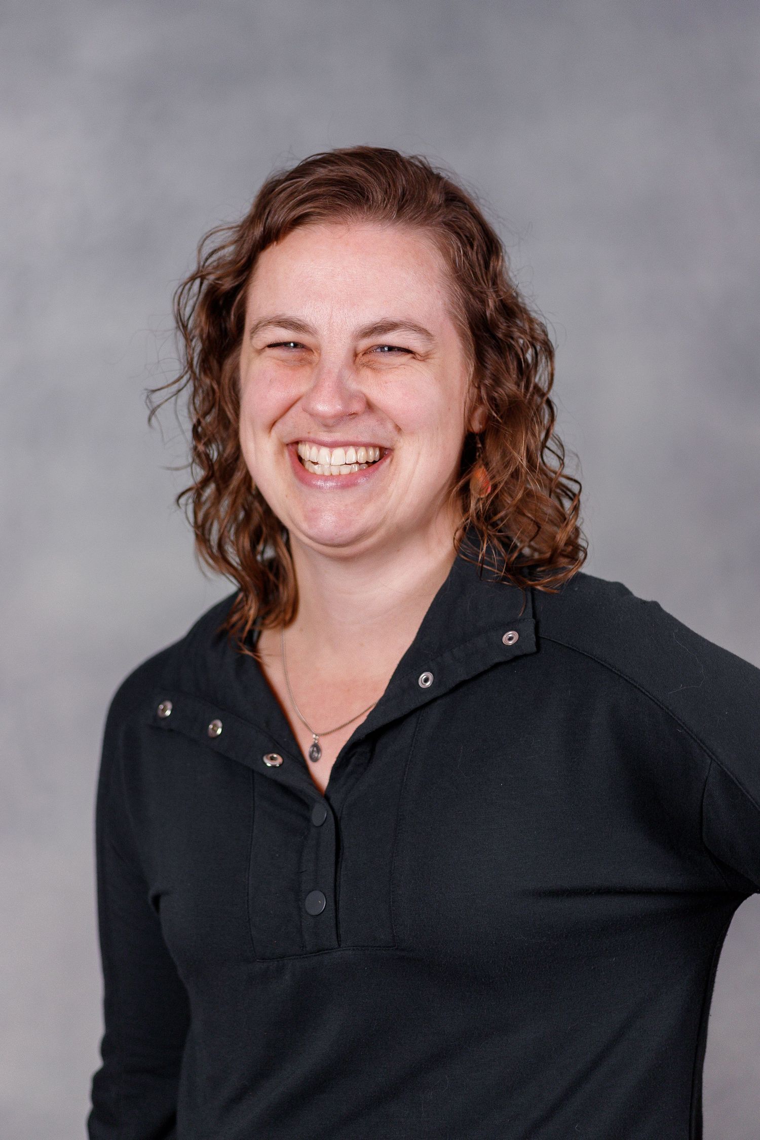 A series of professional headshots showing a person with curly hair in a black shirt against a gray background.