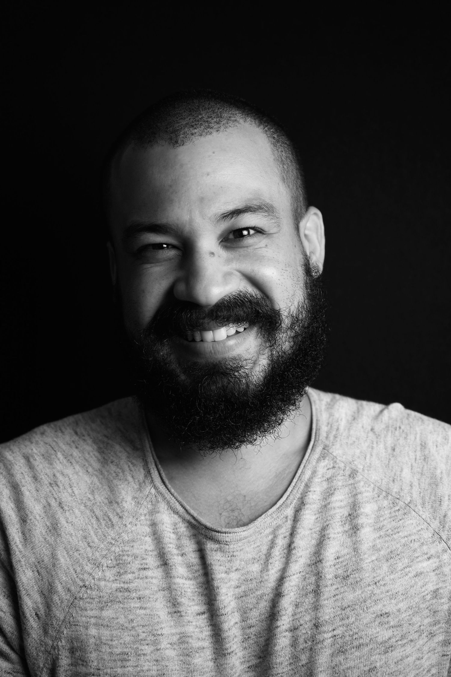 Black and white headshot featuring warm smile and full beard.