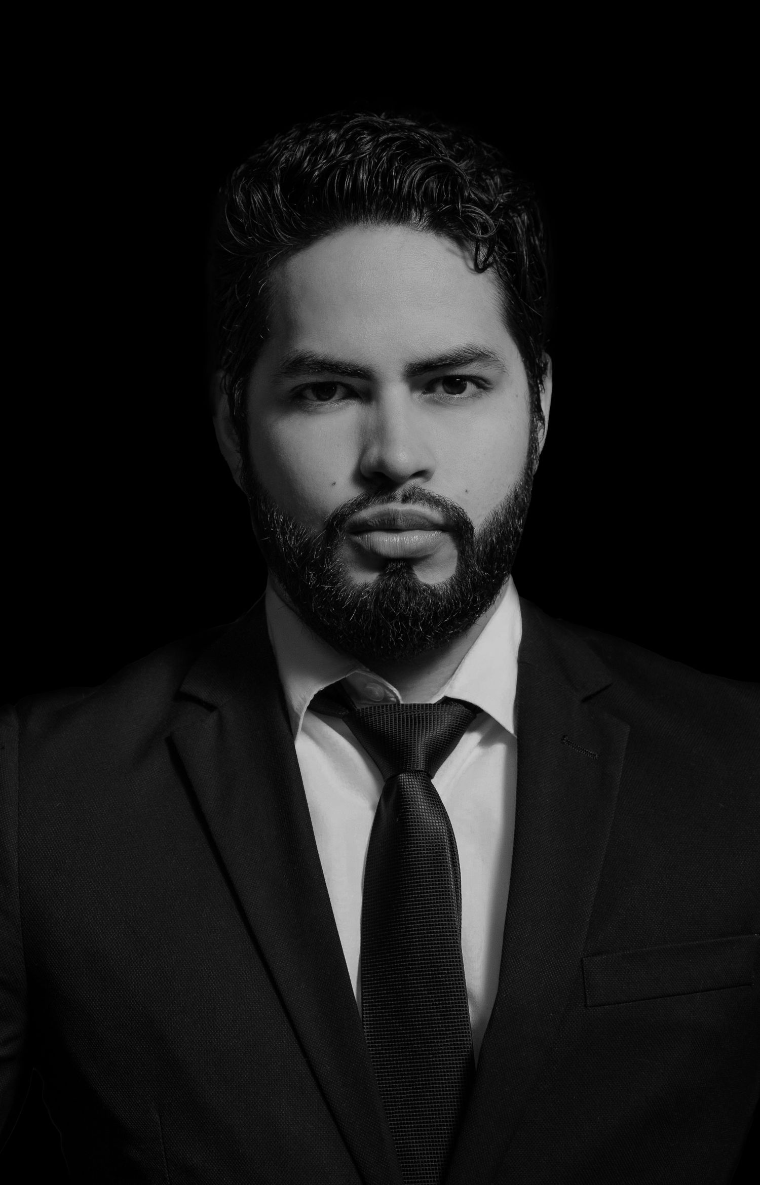 Dramatic black and white portrait in business attire against dark background.