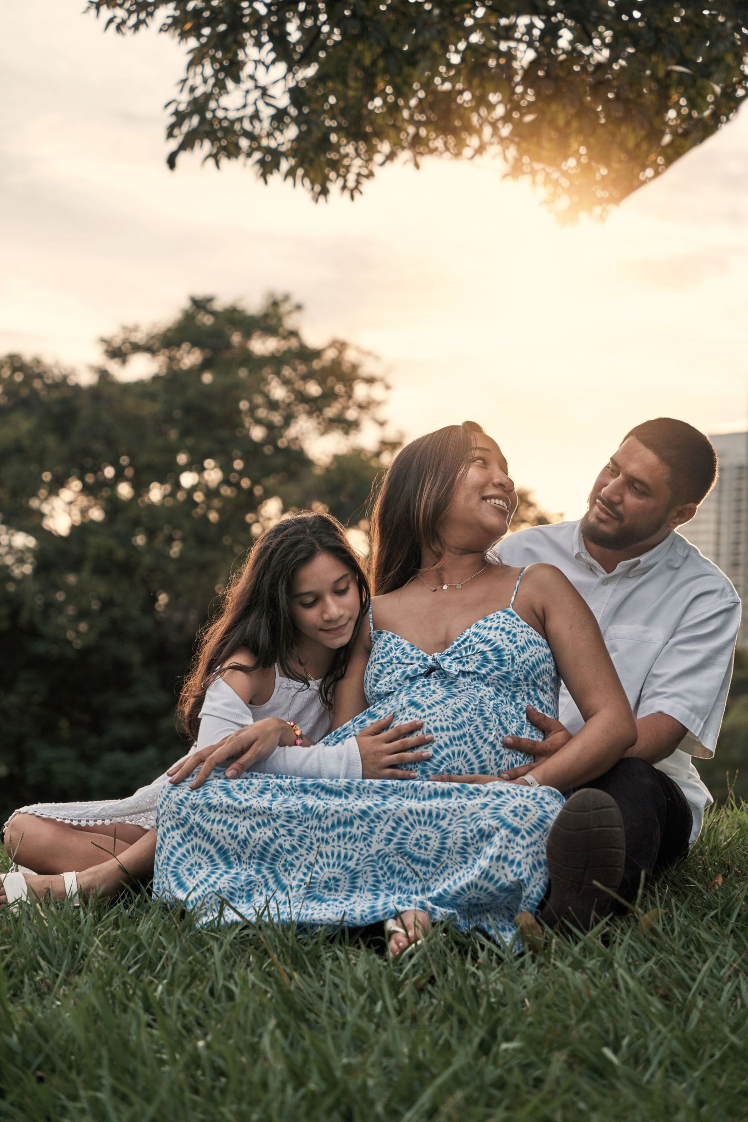A family sits together on grass during sunset creating an intimate outdoor portrait.