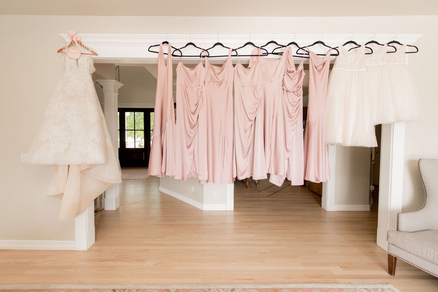 A collection of soft pink and white clothing items hanging on a clothesline against a neutral wall background.