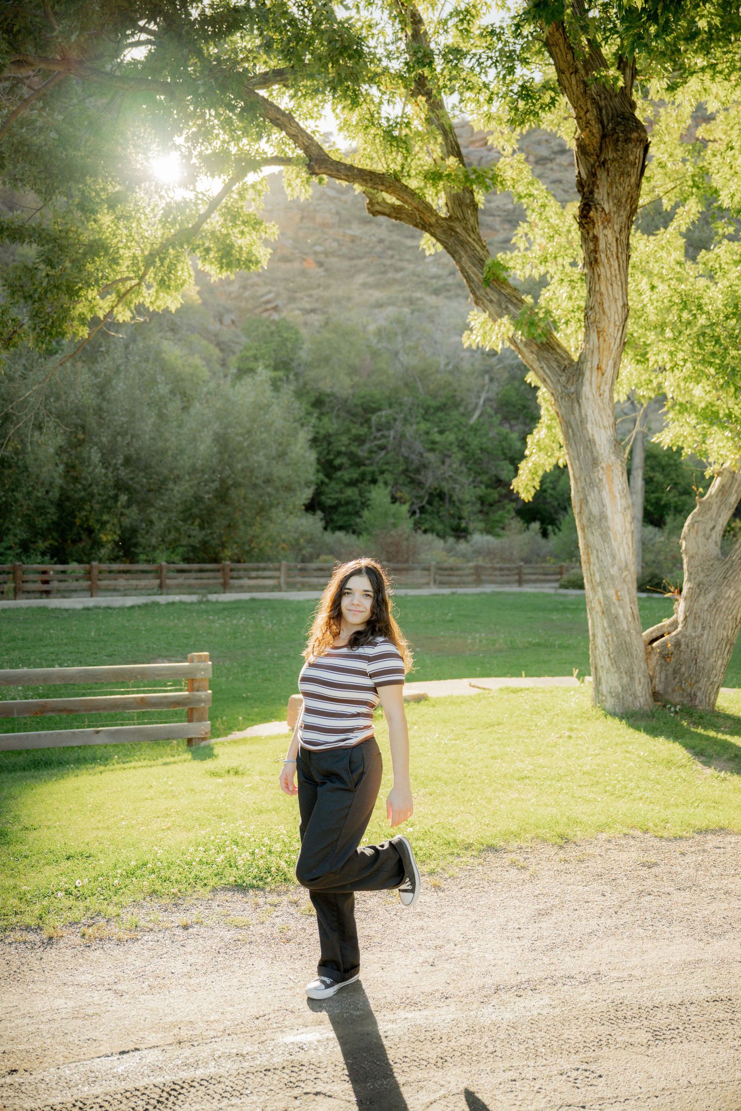 A sequence of photos showing someone in a striped shirt twirling in a sunny park with trees and wooden fences.