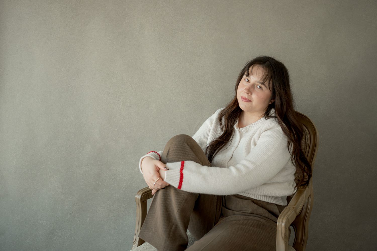 A person in a white sweater lounges on a couch while looking upward in a contemplative pose.