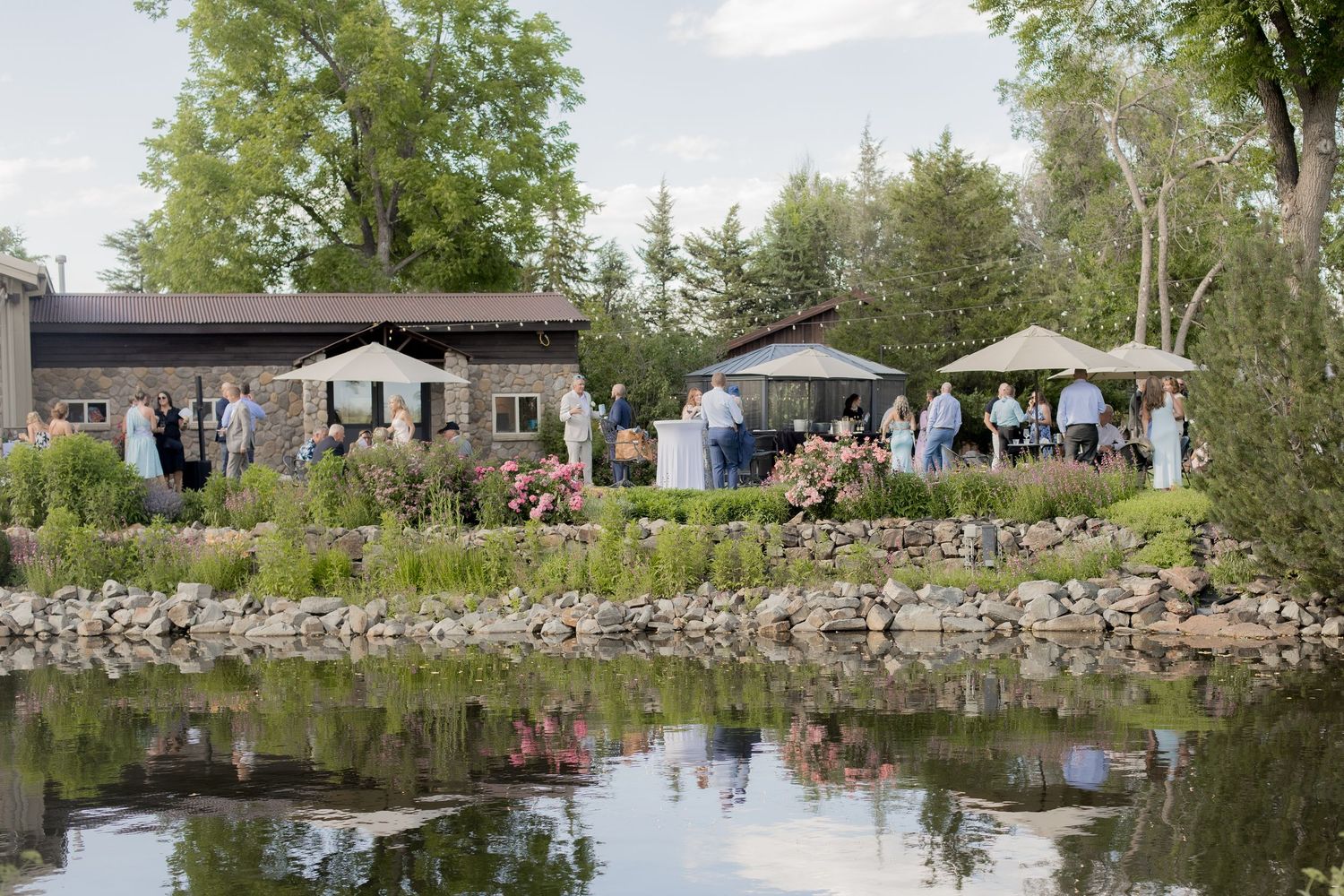 Scenic panoramic view of a tranquil lake surrounded by trees and stone walls with people enjoying the waterfront area.