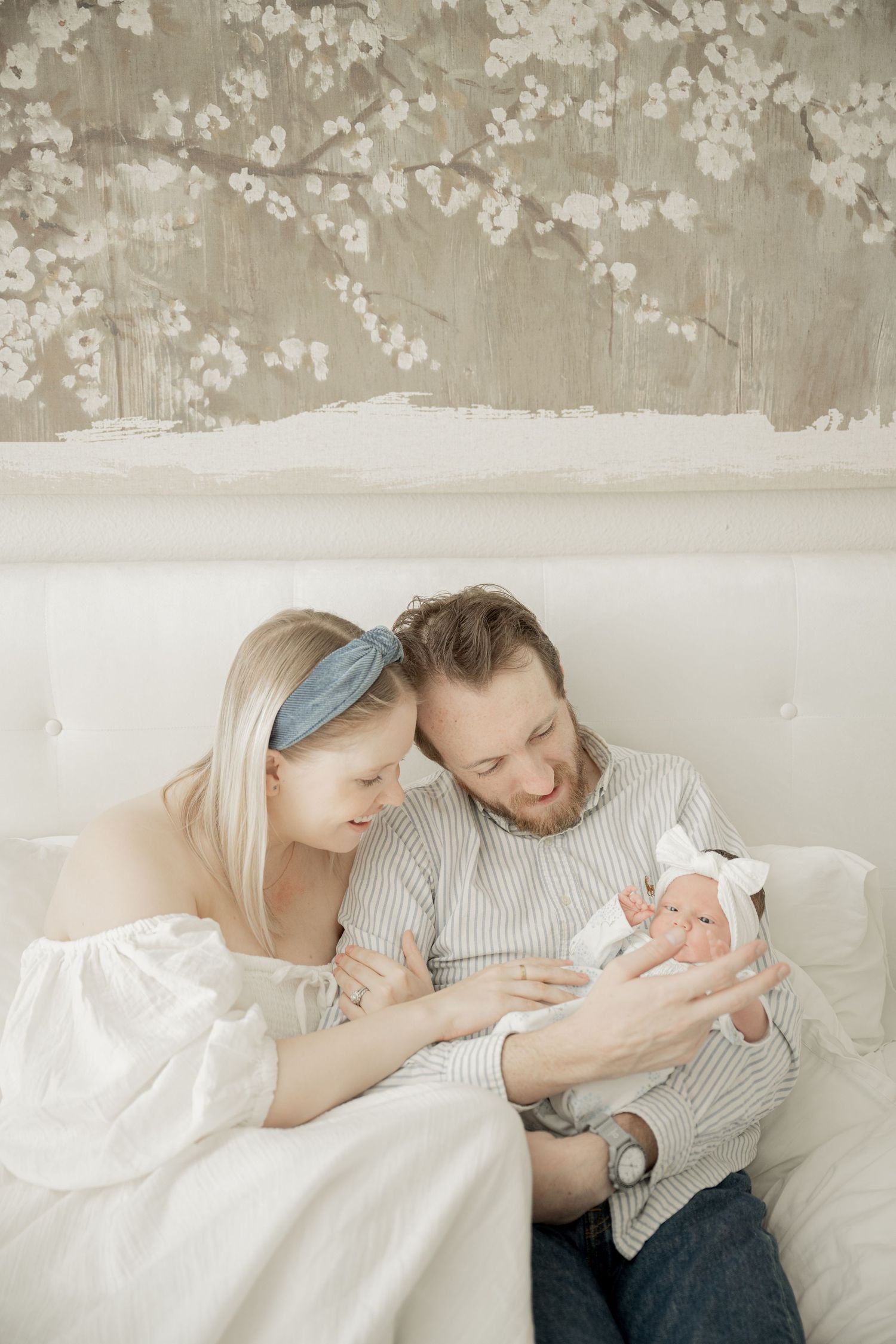 Three tender photos showing a couple lying in bed with white linens against a textured beige wall.