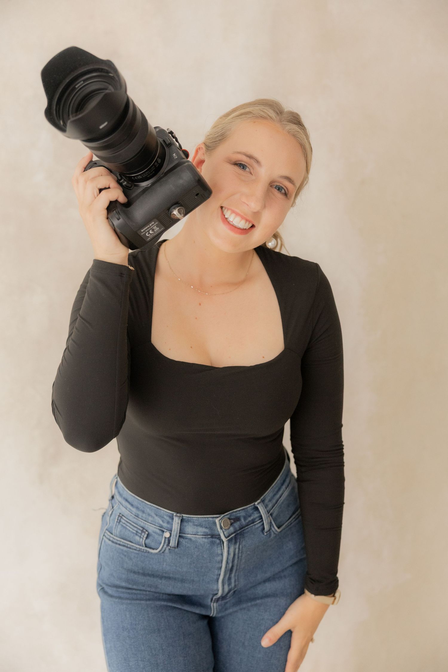 A person wearing a black long-sleeve top and blue jeans poses in a casual photoshoot sequence against a light background.