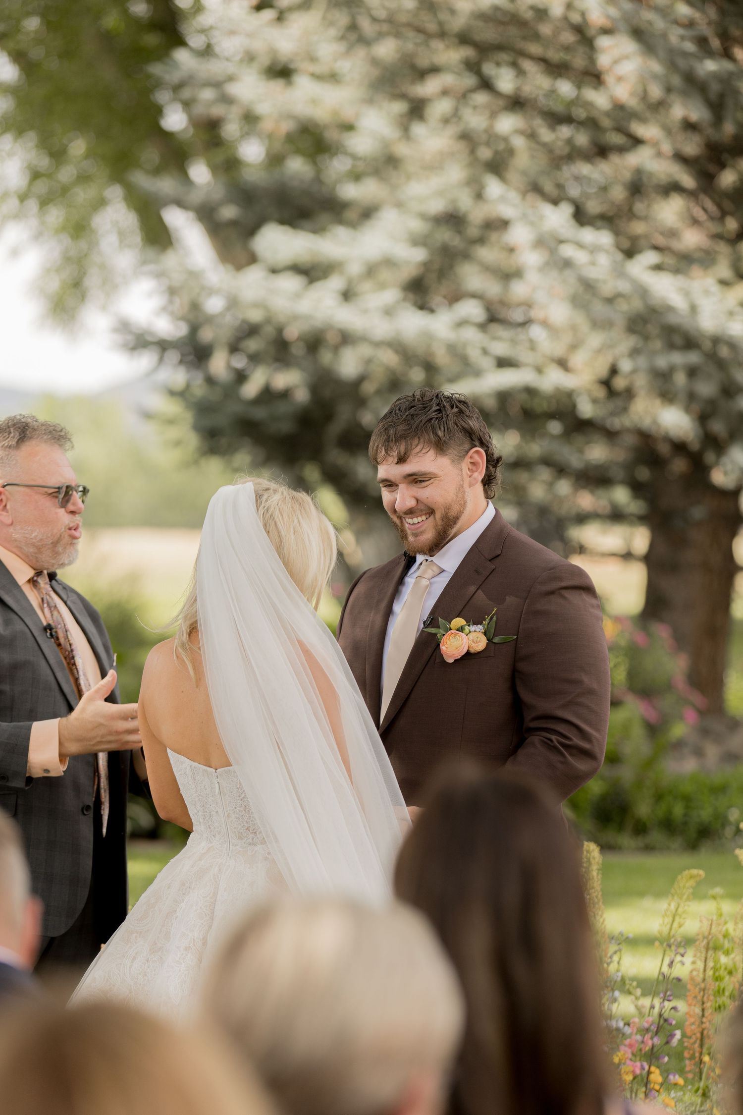 Joyful wedding couple shares candid moments during their outdoor ceremony under blooming trees.
