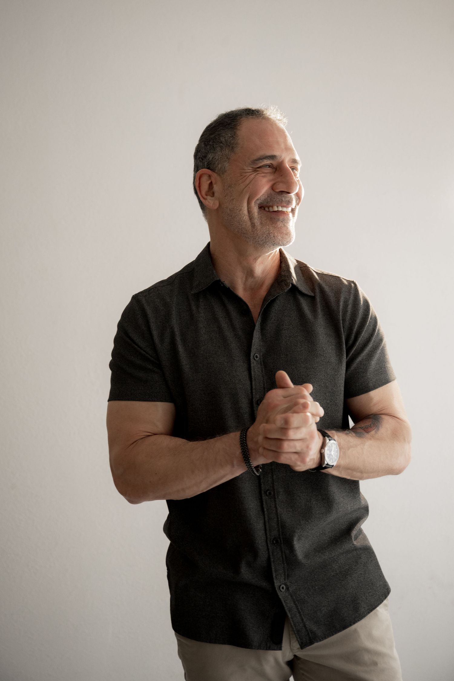 Person wearing black shirt against light background expressing joy and laughter in series of candid poses.